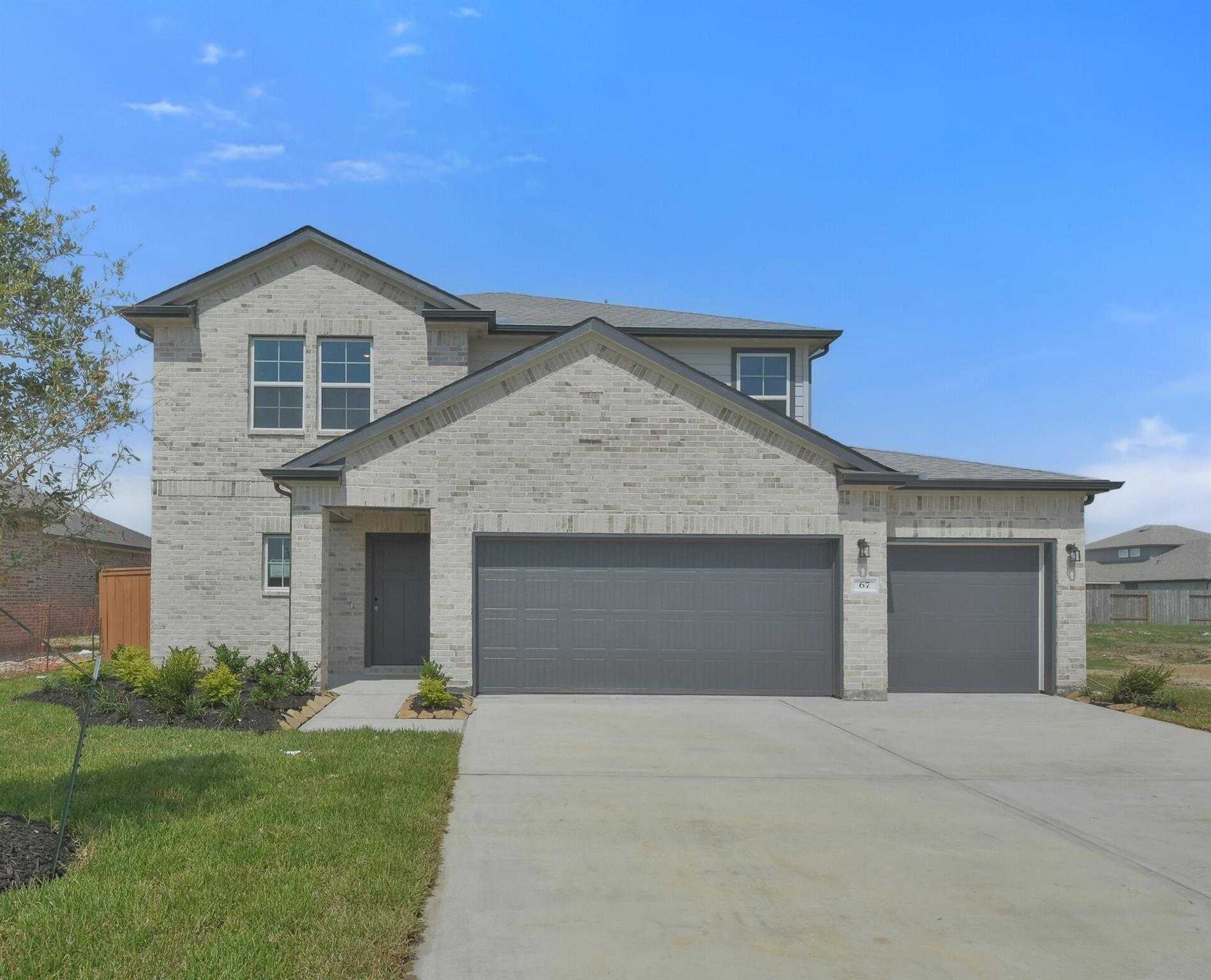 Two-story brick home with 3-car garage, gabled roof, and landscaped yard in River Ranch Meadows, Dayton, Texas by Davidson Homes