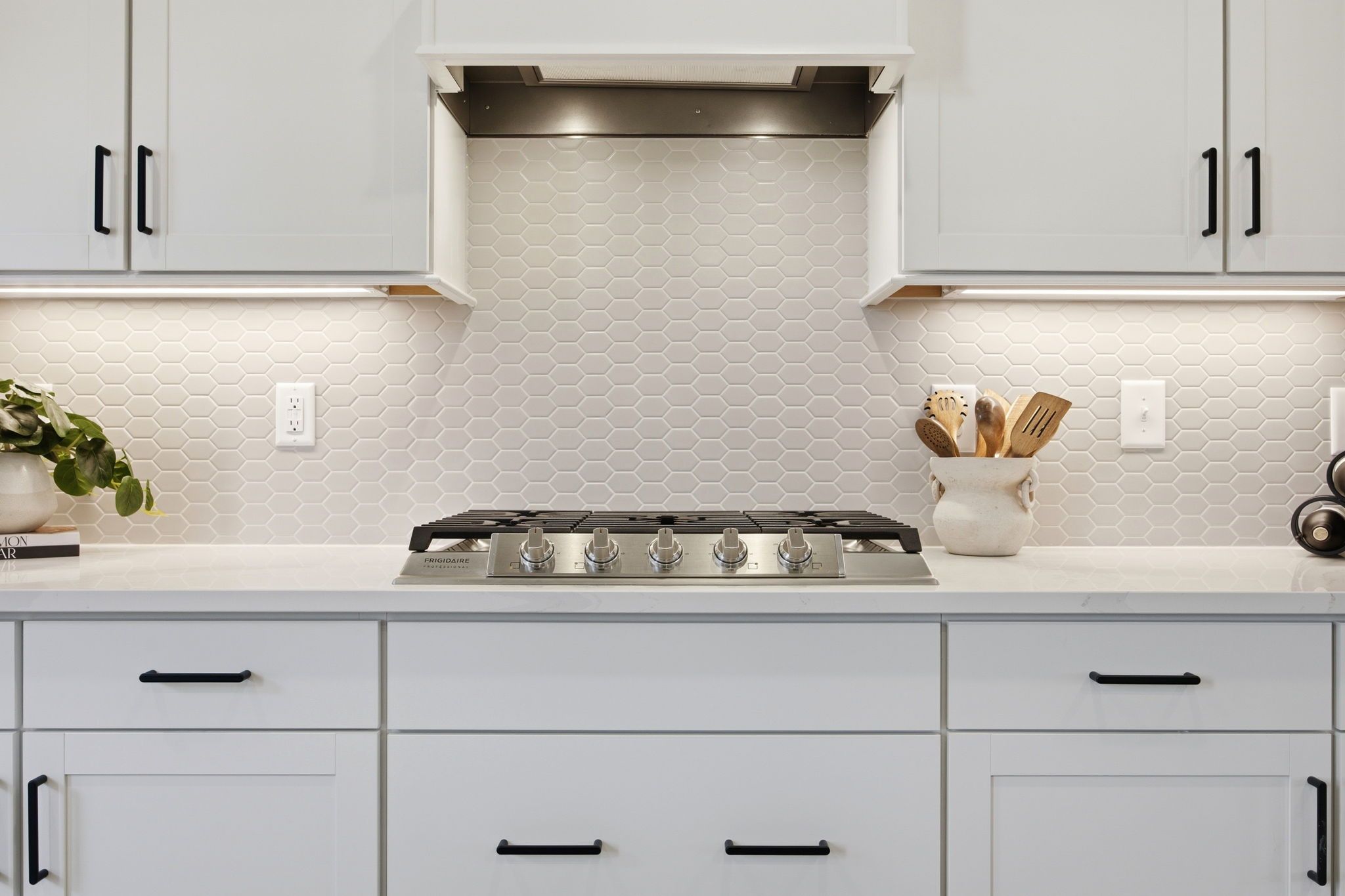 Modern kitchen at Forestville Yard in Knightdale NC with white shaker cabinets, quartz counters, gas range, and hex tile backsplash