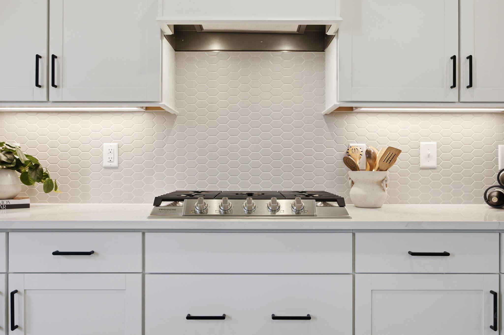 Modern kitchen at Forestville Yard in Knightdale NC with white shaker cabinets, quartz counters, gas range, and hex tile backsplash