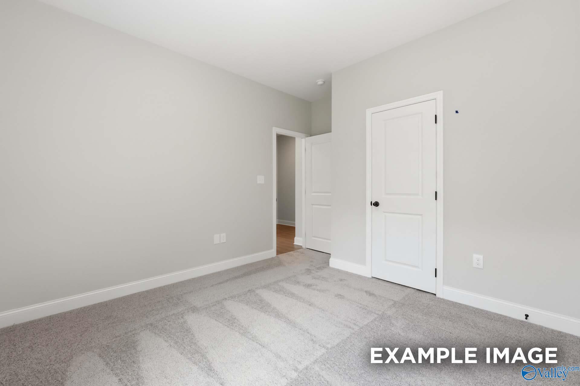Bright, carpeted bedroom with neutral walls and white interior doors in The Franklin C floor plan, The Highlands, Arab, AL.