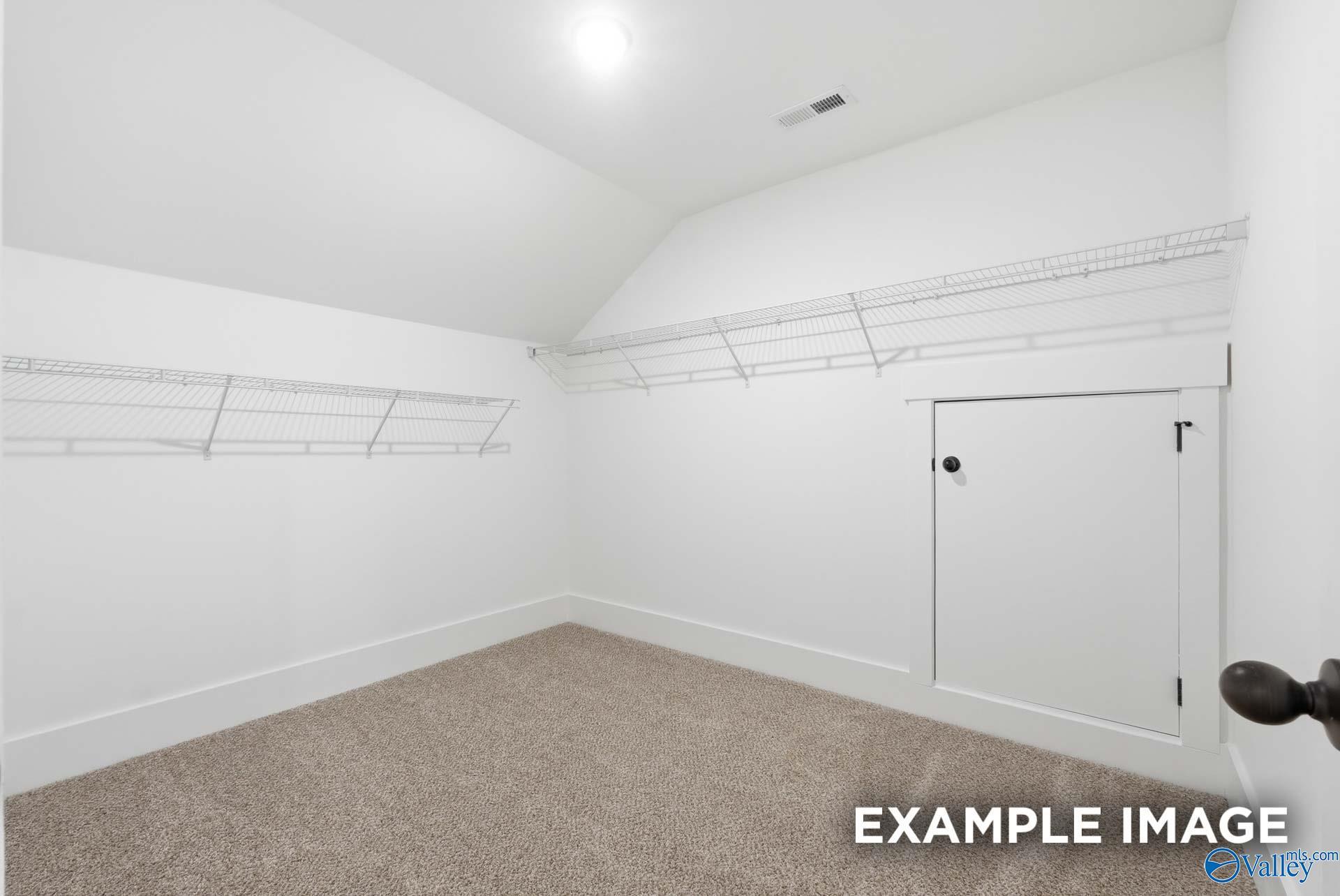 Walk-in closet with carpet and attic access door in The Rockford floor plan home in Briercreek, Meridianville, Alabama.