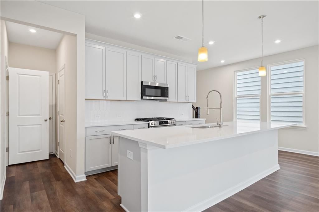 Modern white kitchen with quartz island, stainless appliances, subway tile backsplash in Davidson Homes The Cary B, Kennesaw, GA