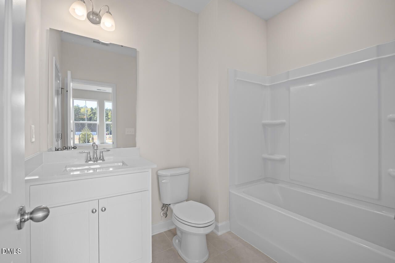 Bright full bathroom with white vanity, tub-shower combo, and toilet in Davidson Homes The Mitchell plan, Knightdale, NC