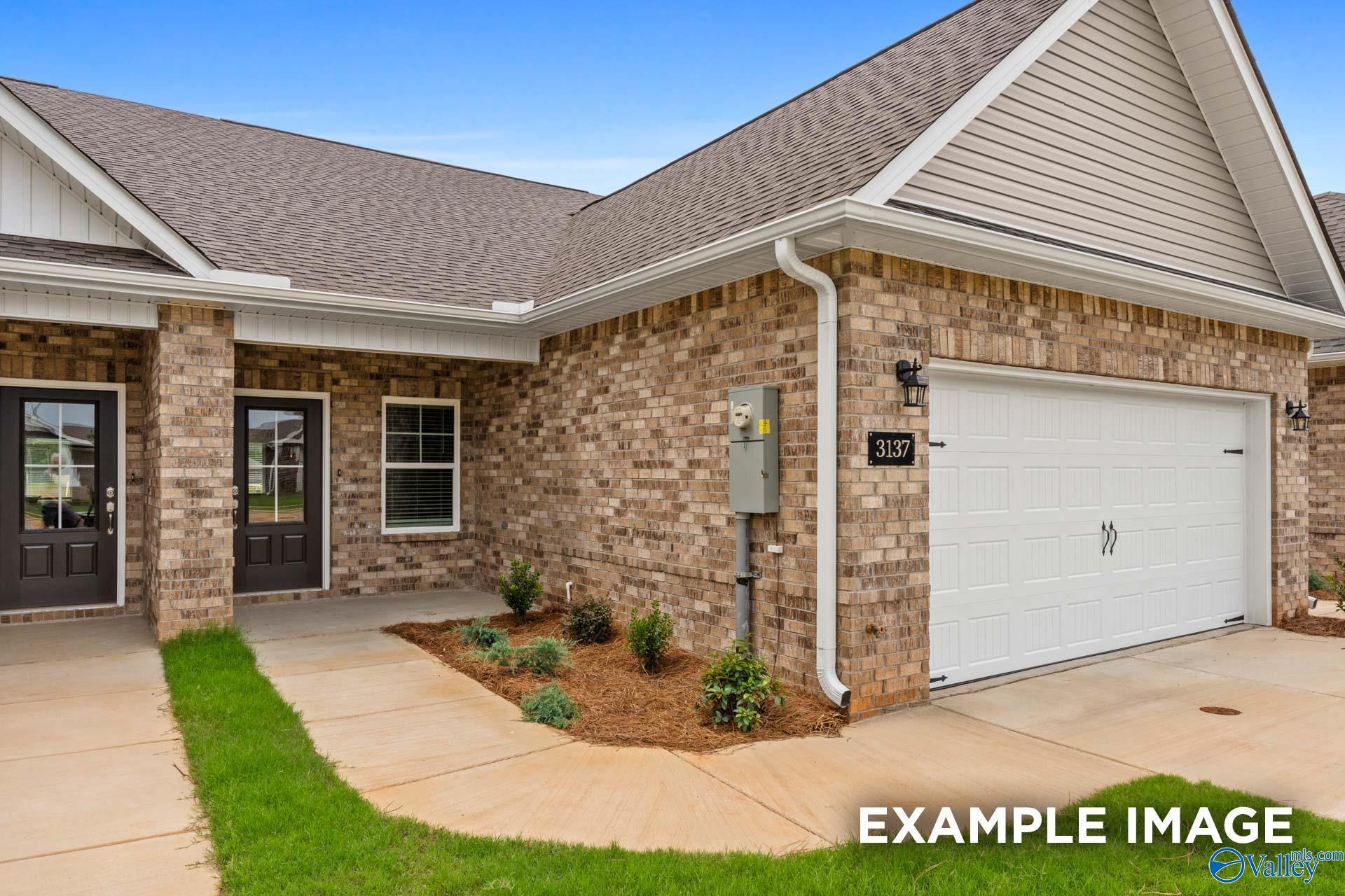 Brick single-story home with 2-car garage, dark wood doors, and landscaped yard in The Retreat at Hollon Meadow, Decatur, Alabama