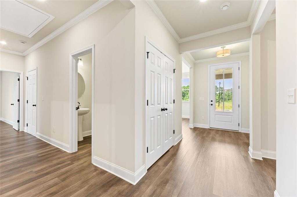 Spacious entry hallway with wood floors, powder room, closet, and glass front door in Davidson Homes The Harrison G, Hoschton, GA