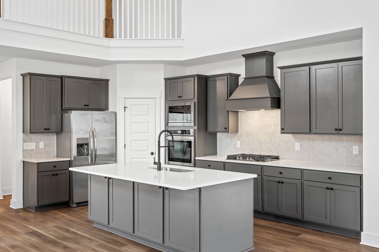 Modern gray shaker kitchen with white quartz island, stainless appliances, and open loft in Davidson Homes Ridgeport, Gallatin TN