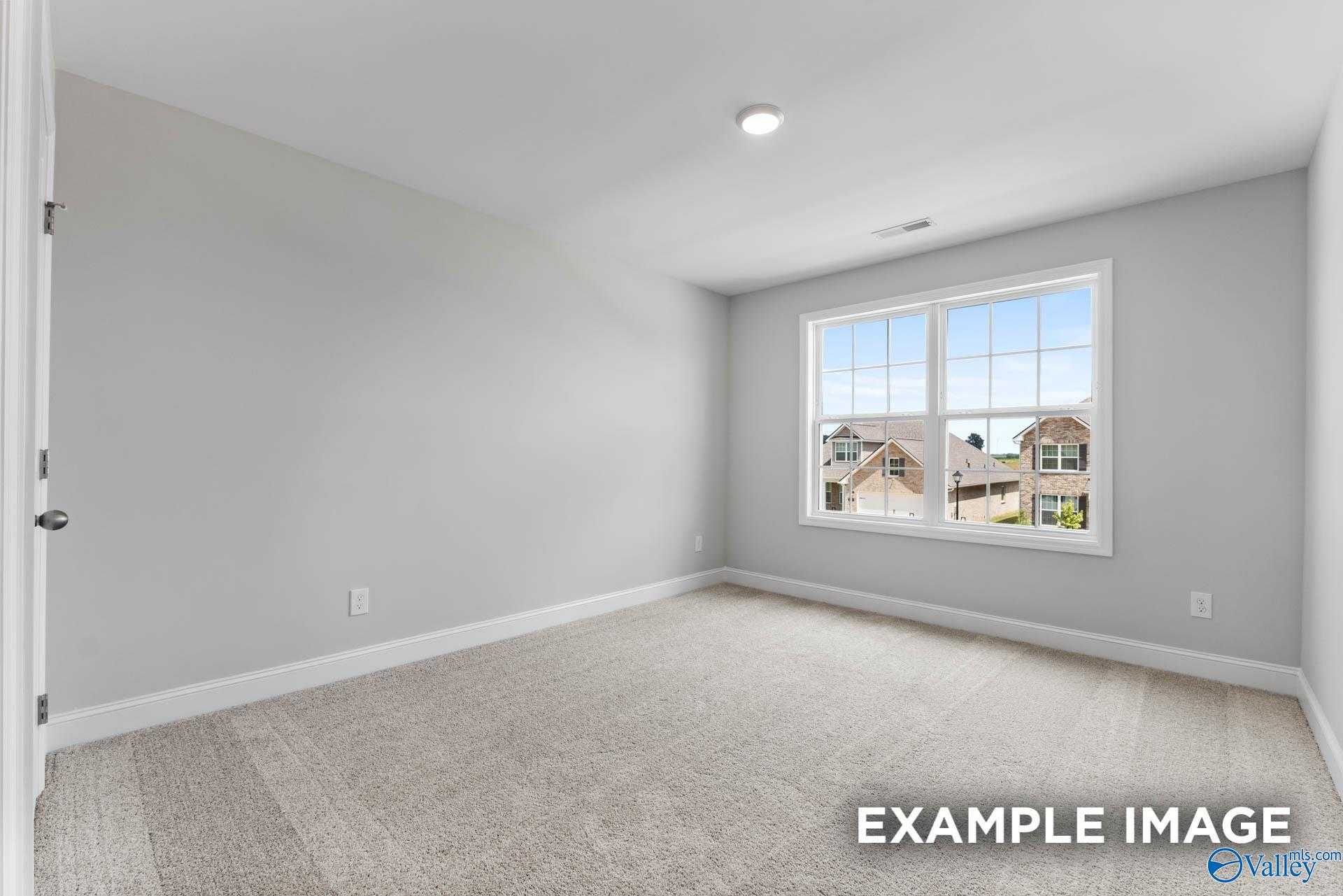 Bright secondary bedroom with gray walls, carpet floor, and window overlooking neighborhood in Davidson Homes The Madison A, Harvest AL