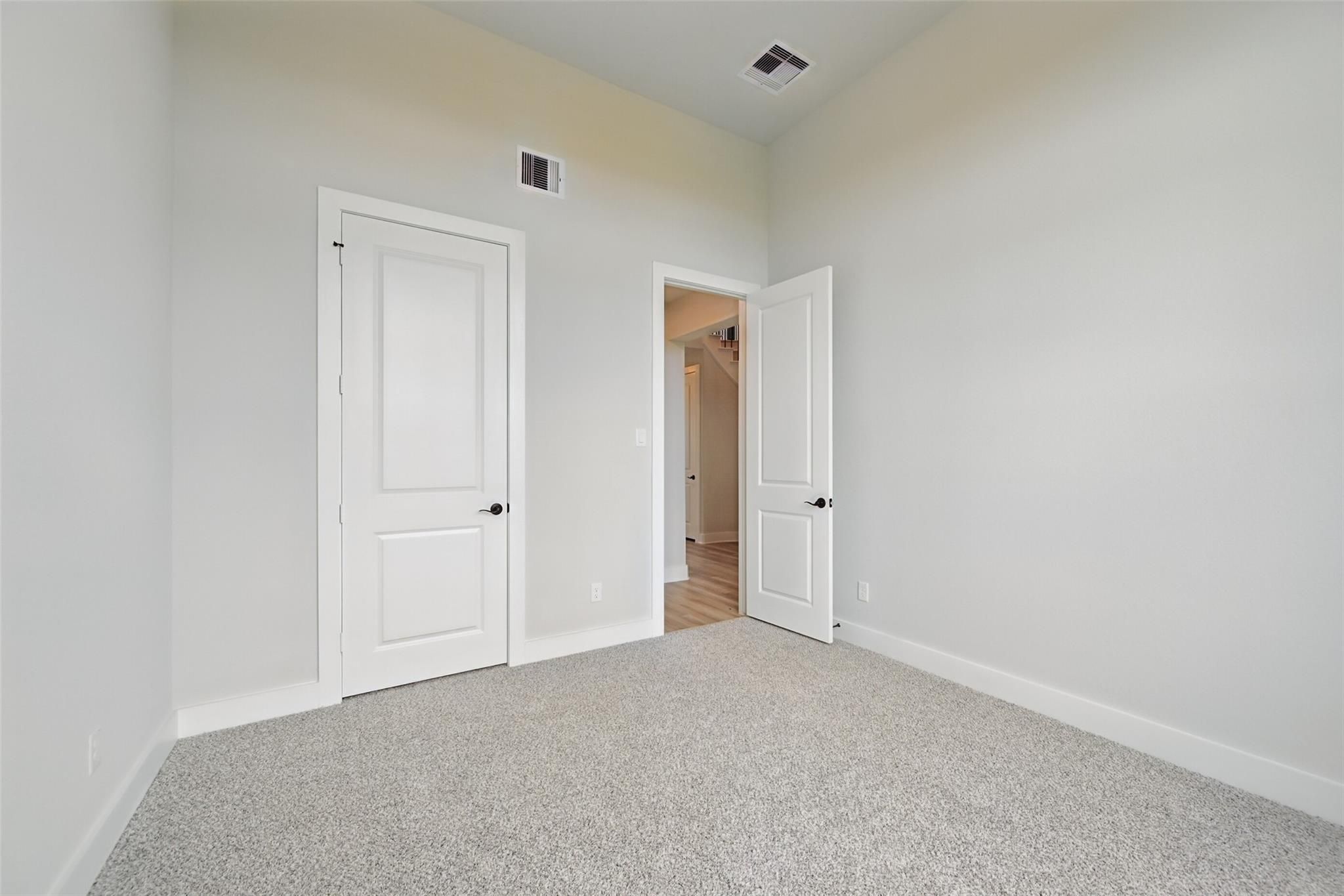 Spacious bedroom with gray carpet flooring, white paneled doors to hallway in 4-bedroom Davidson Homes The Victoria C, Lago Mar, Texas City