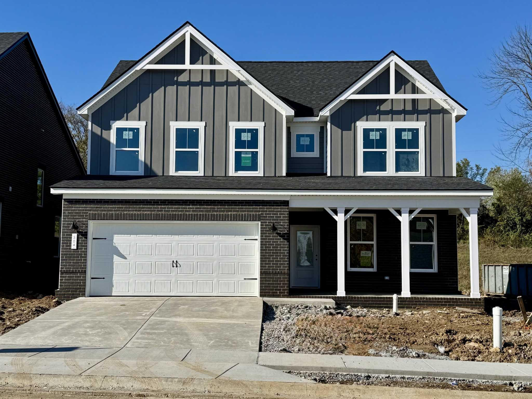 Modern two-story 4-bedroom Davidson Homes Willow B with gray siding, covered porch, 2-car garage in Woods Crossing, Gallatin, TN