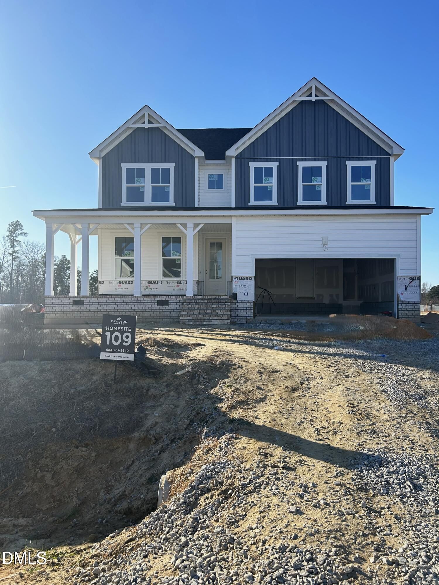 Modern two-story 4-bedroom home with navy blue siding, columned front porch, 2-car garage, and Davidson Homes sign in Tobacco Road, Angier, NC