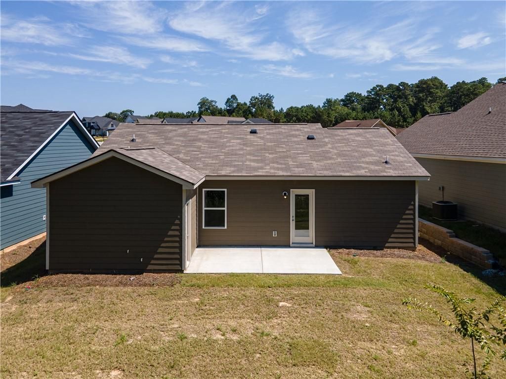Rear view of Davidson Homes The Washington single-story home with covered patio, brown siding, and grassy backyard in Summer Vineyard, Phenix City, Alabama