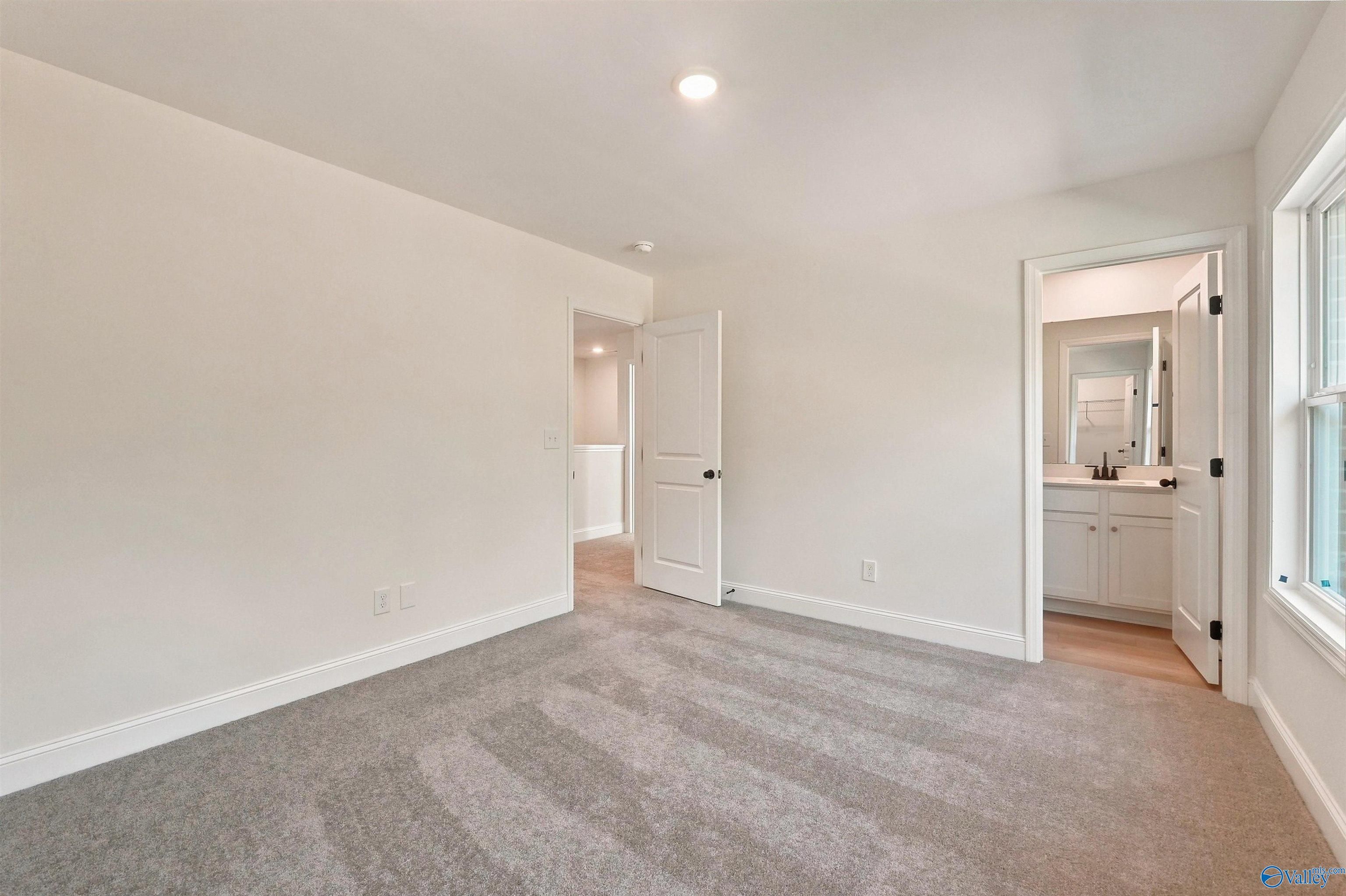 Bright bedroom with plush carpet and en-suite bathroom in The Chelsea C floor plan at Creek Grove, New Market, Alabama.