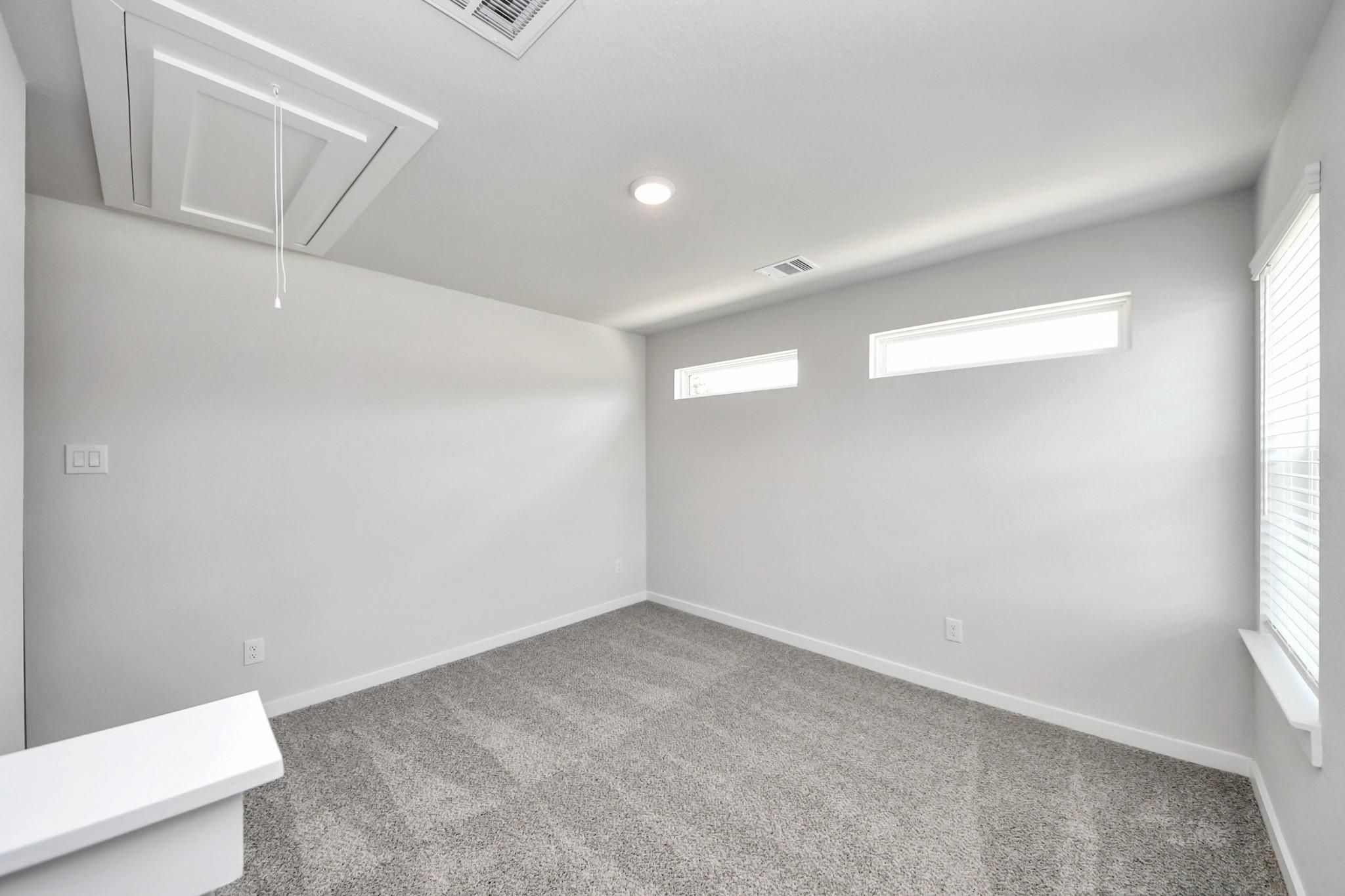 Bright, carpeted bedroom with transom windows in The Sabine E floor plan at Liberty Estates, Cleveland, Texas.