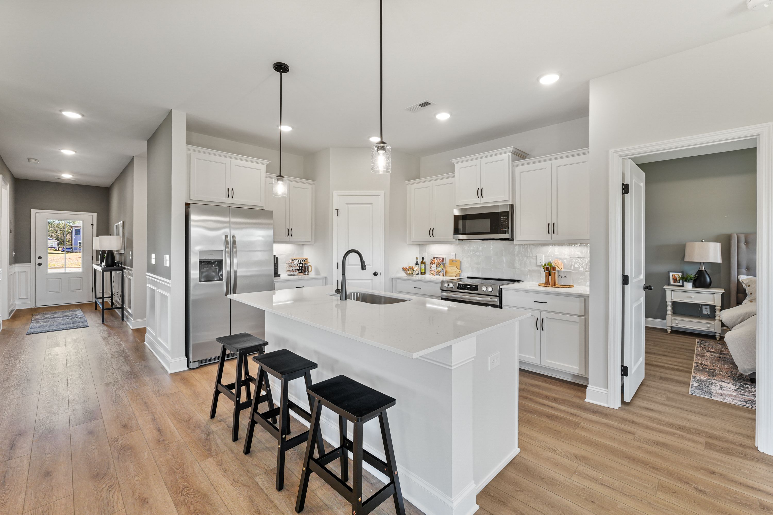Spacious modern kitchen in Ramsay Cove, Owens Cross Roads AL with white cabinets, large island, stainless appliances, hardwood floors