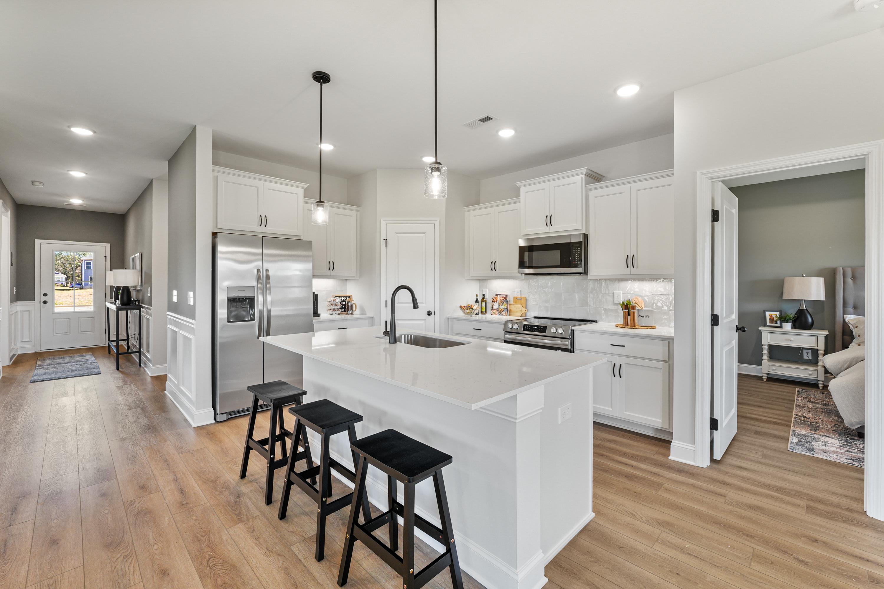 Spacious modern kitchen in Ramsay Cove, Owens Cross Roads AL with white cabinets, large island, stainless appliances, hardwood floors