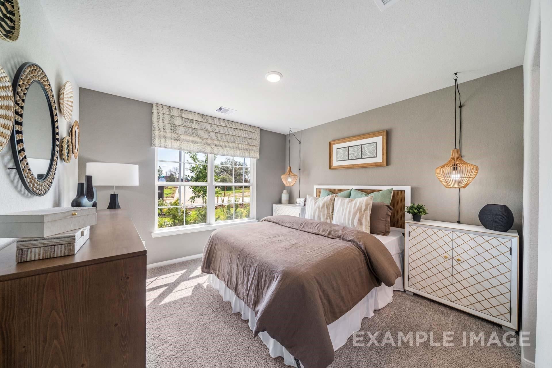 Cozy bedroom featuring king bed with neutral bedding, woven wall mirrors, and garden-view windows in Davidson Homes The Acadia A, Texas City
