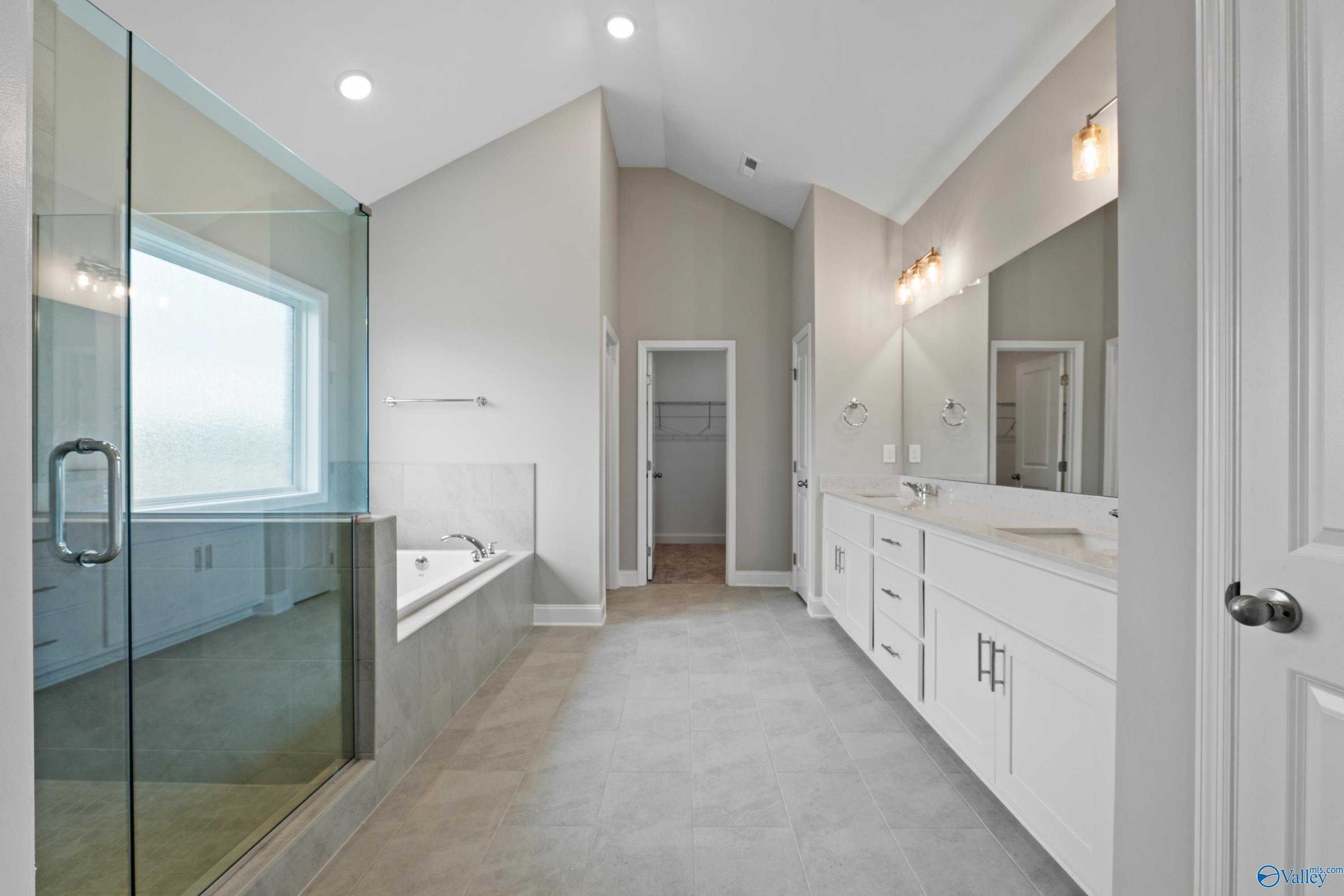 Elegant master bathroom with frameless glass shower, freestanding tub, and double vanity in Davidson Homes The Finleigh, Meridianville