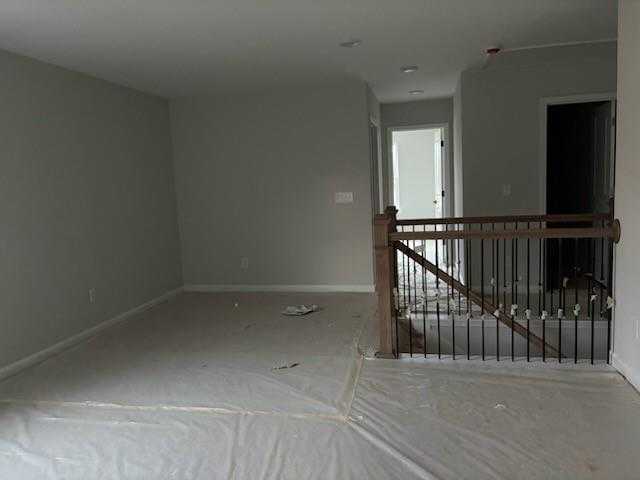 Spacious empty upstairs hallway with wooden balustrade and gray walls in Davidson Homes The Rabun C, Winder, Georgia
