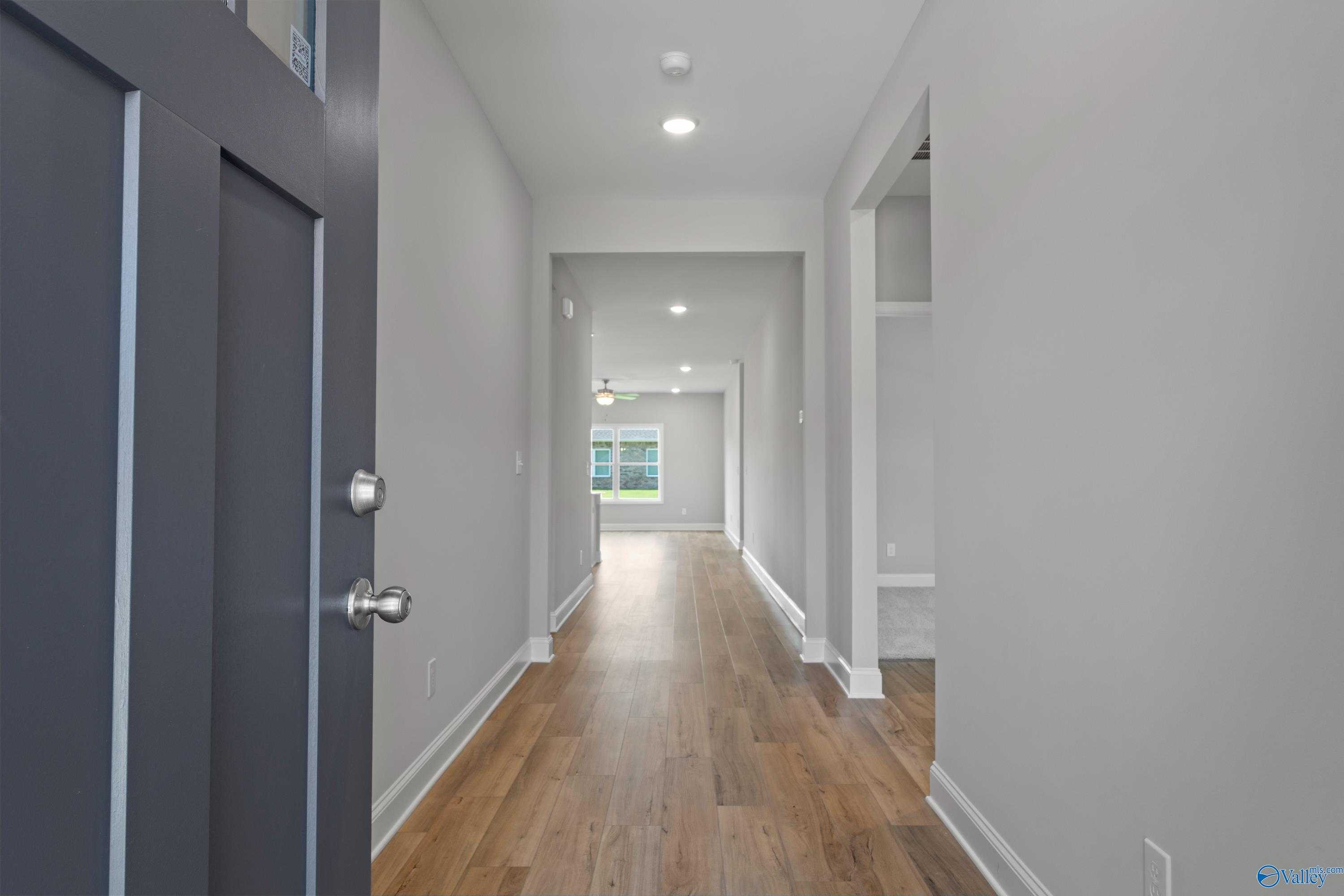 Spacious hallway with hardwood floors, white walls, and natural light in Davidson Homes The Daphne C, Athens Alabama
