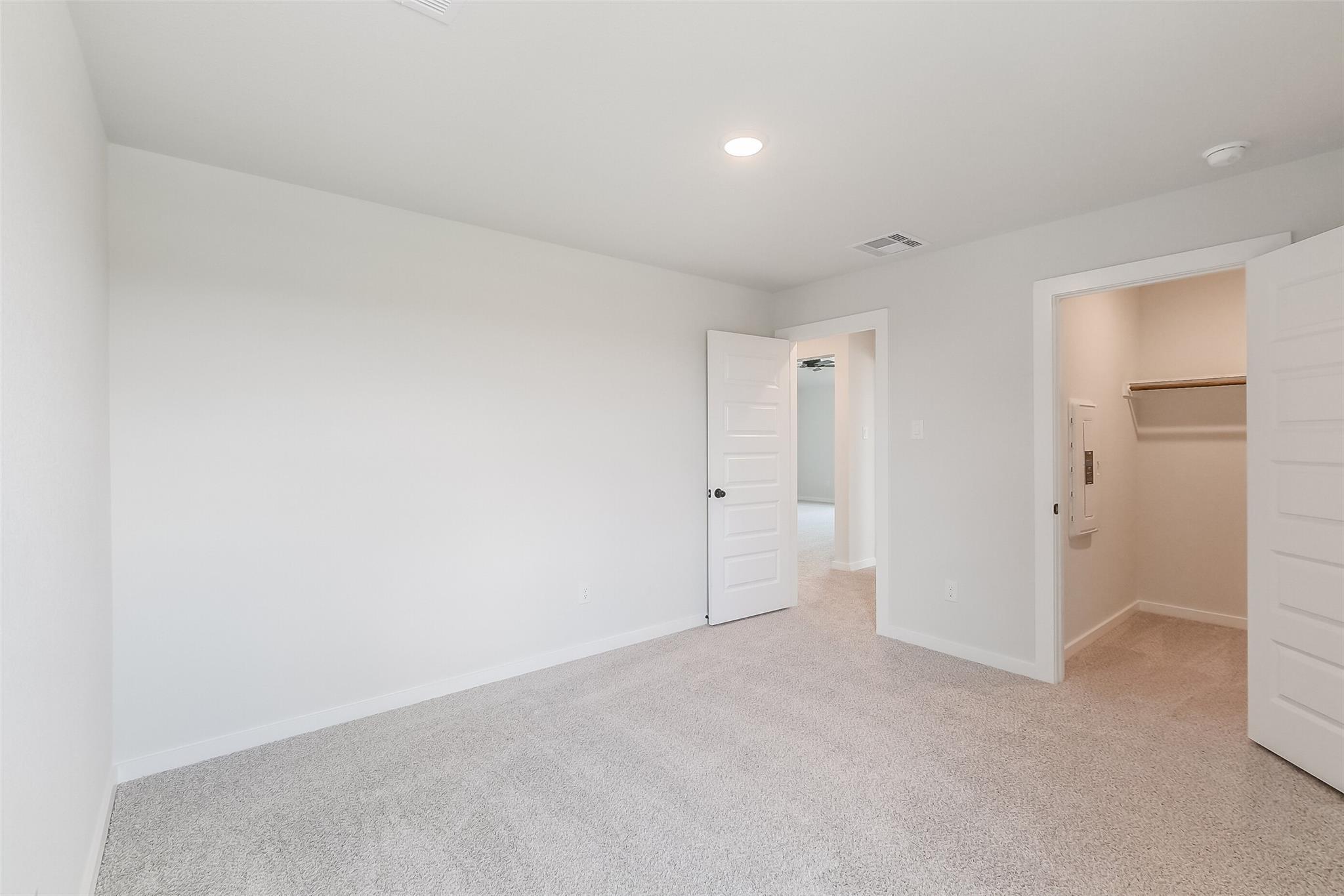Bright secondary bedroom with adjacent closet and neutral carpet in Davidson Homes The Tierra B, Emberly, Beasley, Texas