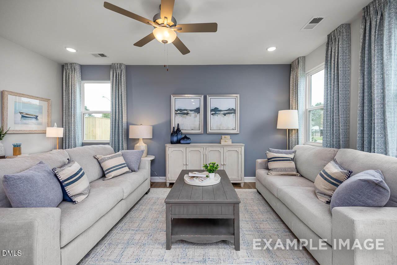 Cozy living room with gray sofas, blue accent wall, ceiling fan in Davidson Homes The Graham Interior, Fuquay-Varina, NC