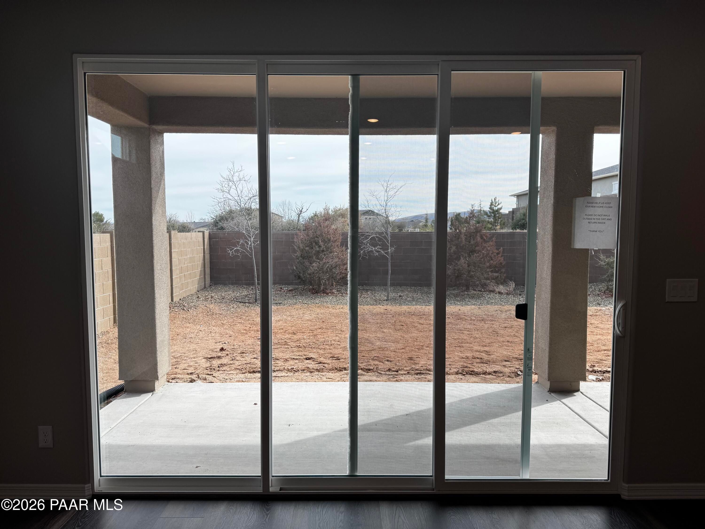 Sliding glass doors to covered patio overlooking dirt backyard, shrubs, and mountain views in Westwood Prescott AZ home