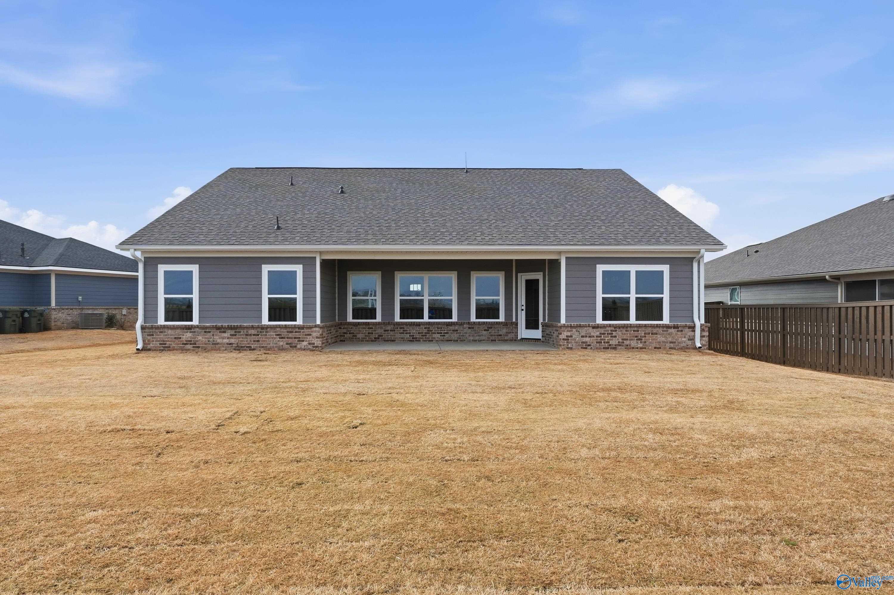 Modern gray single-story home with stone accents, large windows, and fenced yard in Anderson Farm, Athens, Alabama