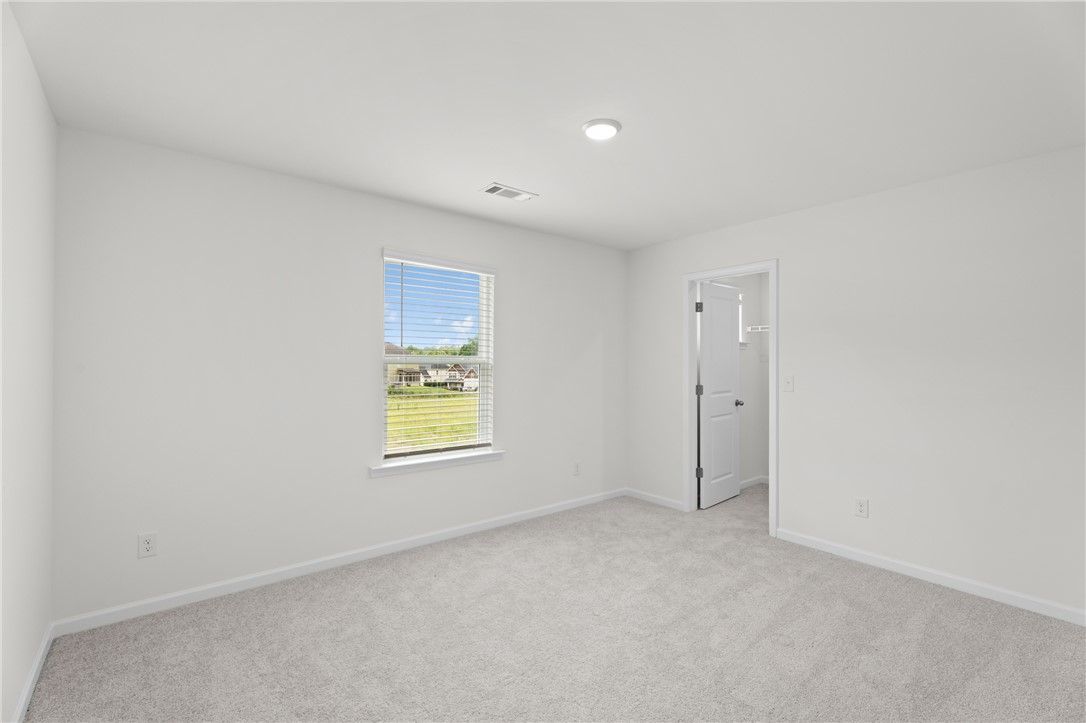 Bright, carpeted bedroom with walk-in closet in The Stella D floor plan by Evermore Homes in Silver Oak, Cusseta, Alabama.