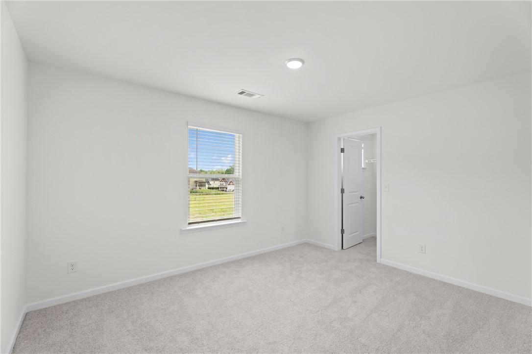Bright, carpeted bedroom with walk-in closet in The Stella D floor plan by Evermore Homes in Silver Oak, Cusseta, Alabama.