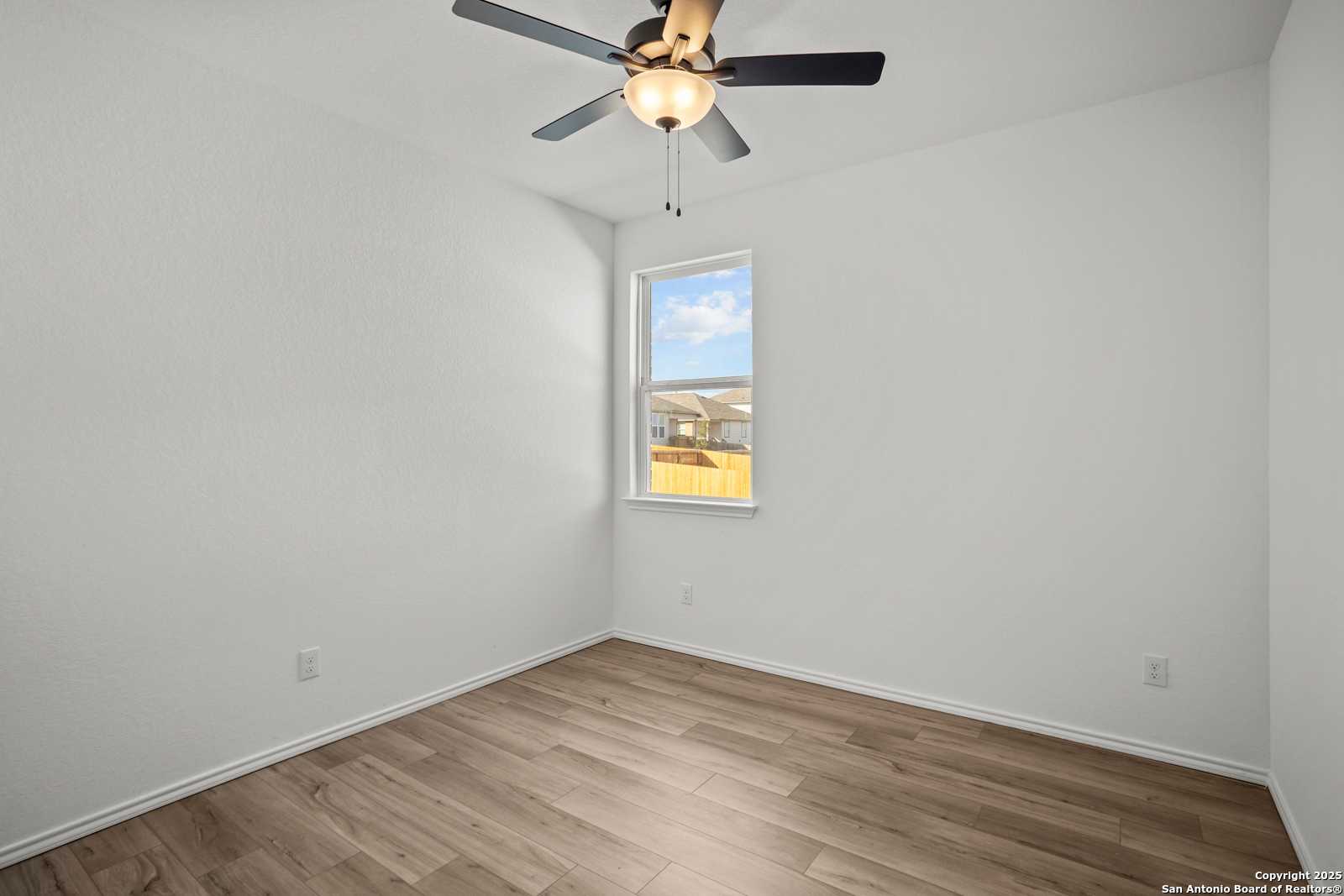 Bright secondary bedroom with white walls, ceiling fan, and window view in Davidson Homes The Daphne K, San Antonio