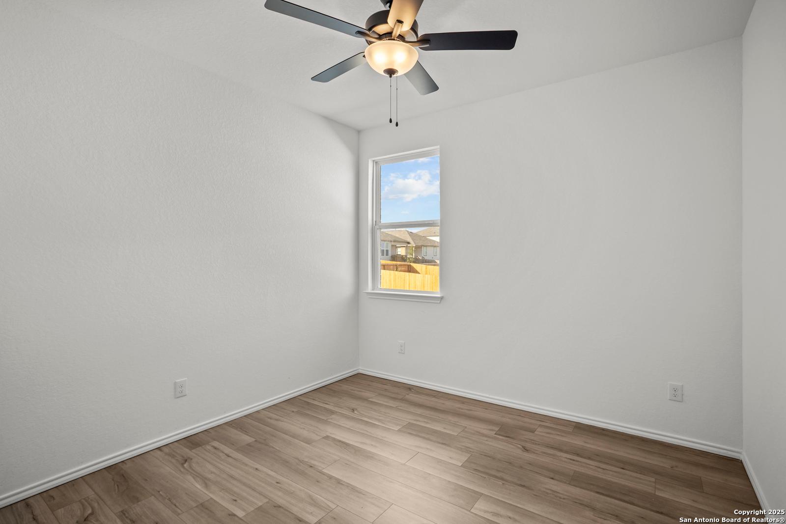 Bright secondary bedroom with white walls, ceiling fan, and window view in Davidson Homes The Daphne K, San Antonio