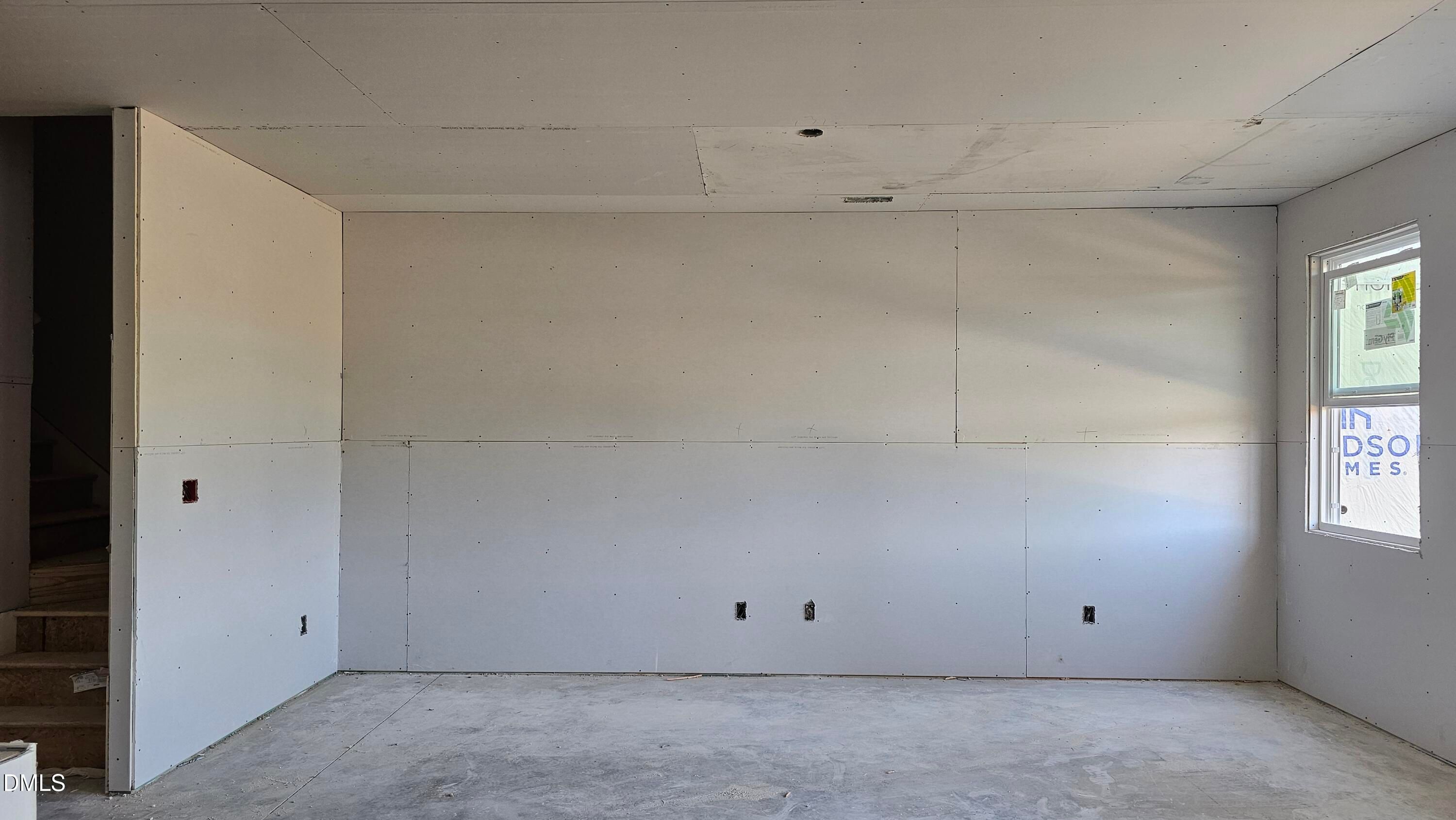 Unfinished living area with drywall and concrete floors in The Graham Interior floor plan at Springvale, Fuquay-Varina.