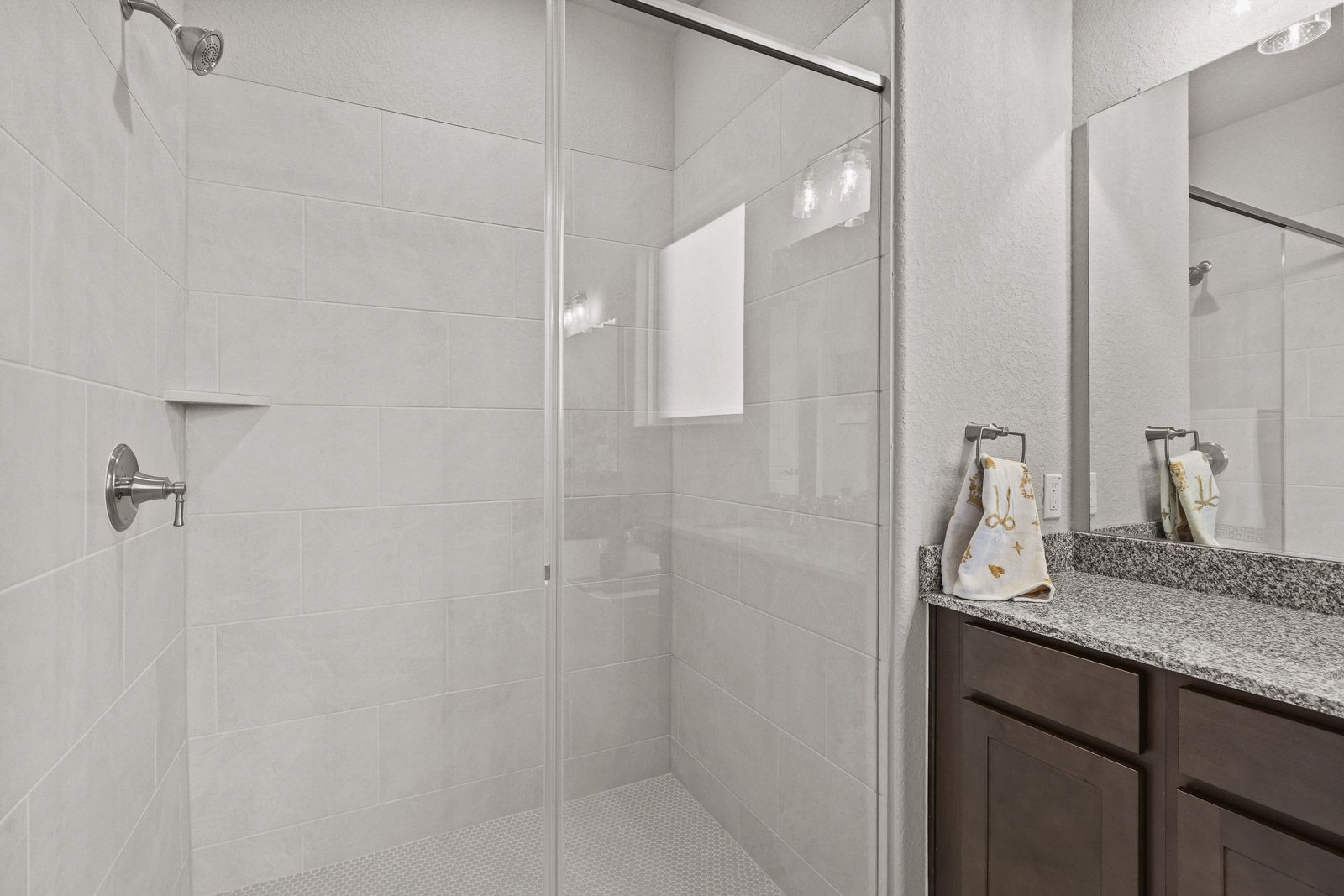 Modern bathroom in The Jennings G featuring a glass-enclosed tiled shower and granite vanity countertop.