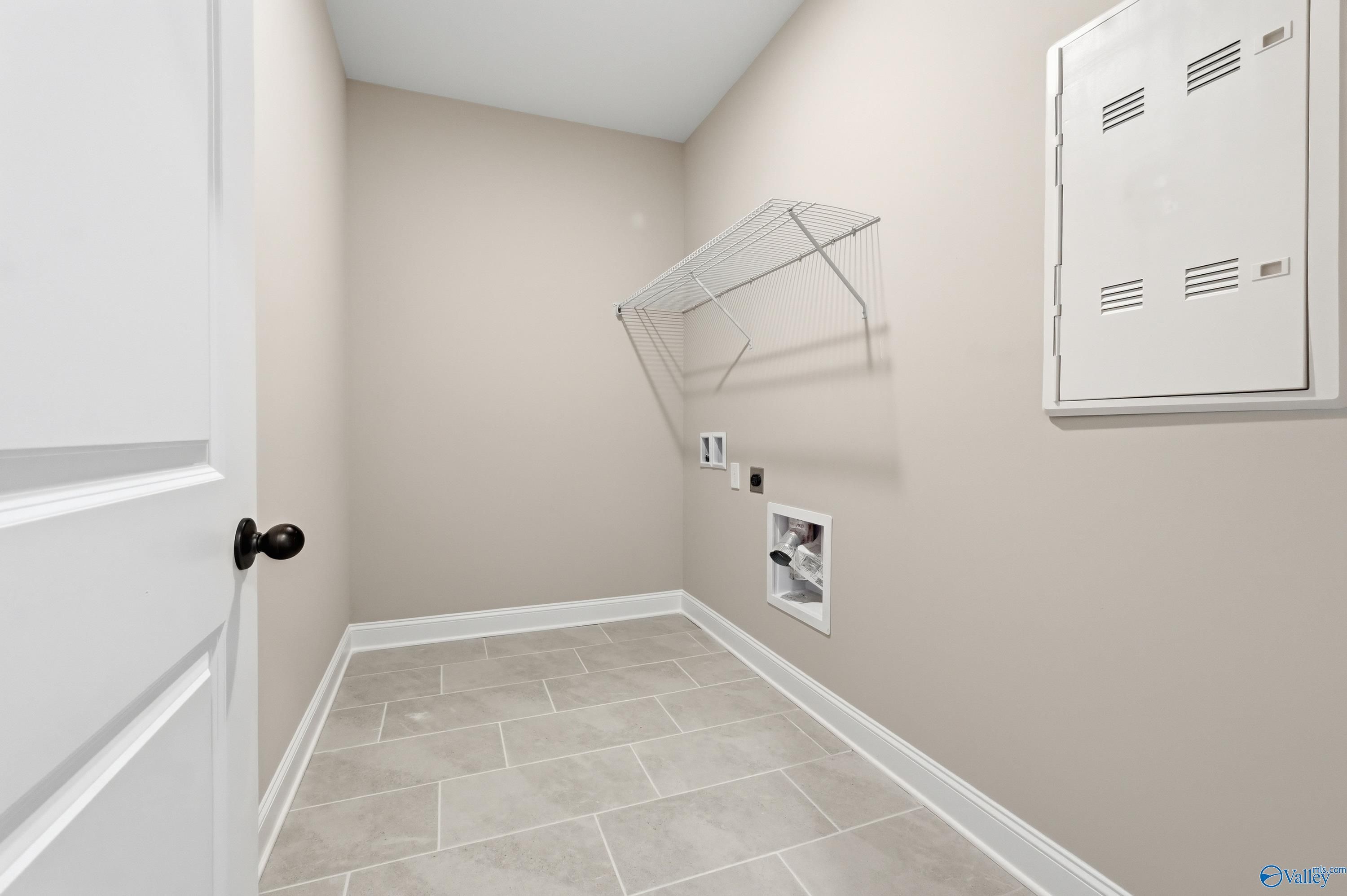 Spacious laundry room with wire shelving, washer-dryer hookups, and beige tile floor in Davidson Homes The Rockford, Harvest AL
