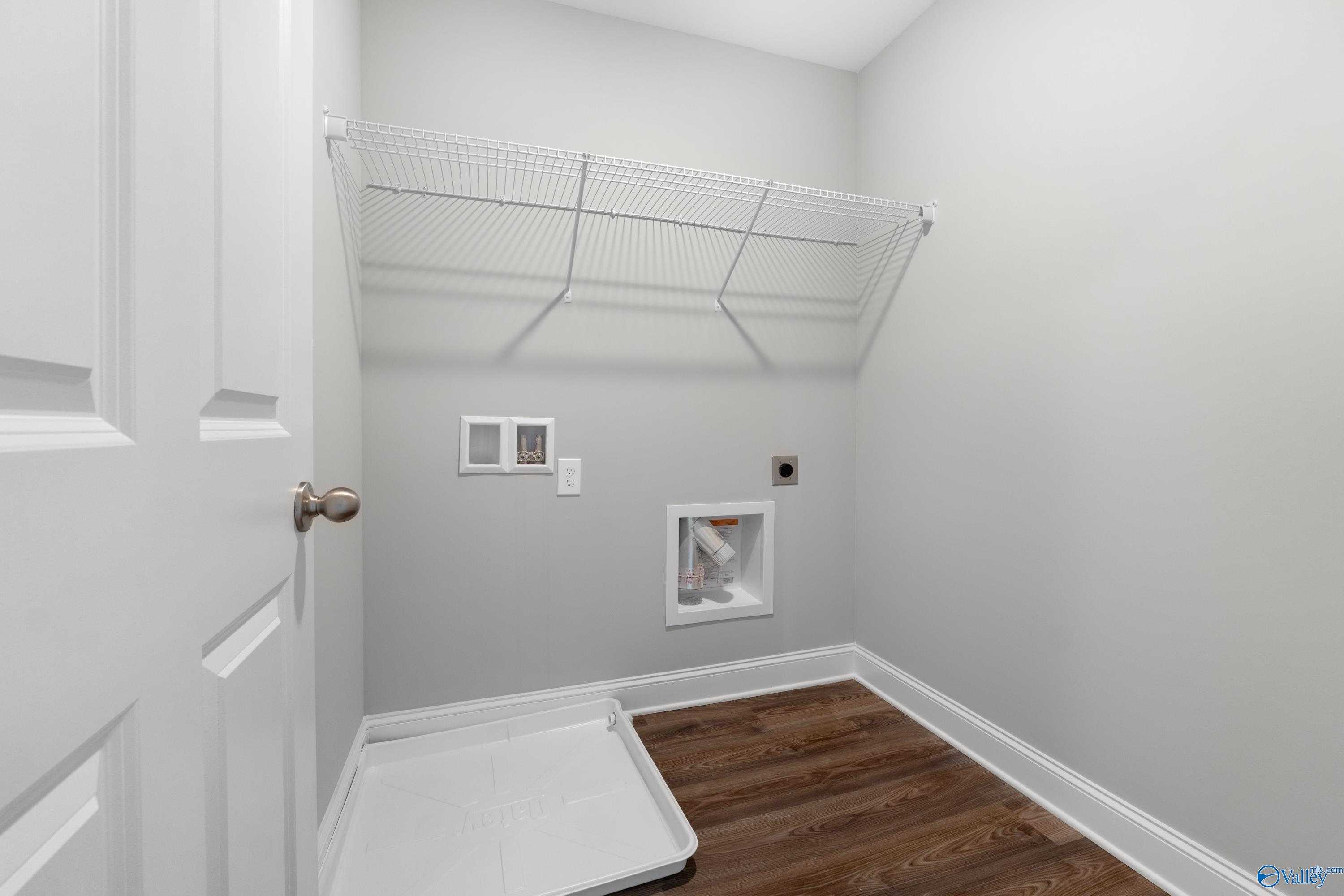 Functional laundry room with white wire shelving, washer dryer hookups, gray walls in The Aiken floor plan, Meridianville, Alabama