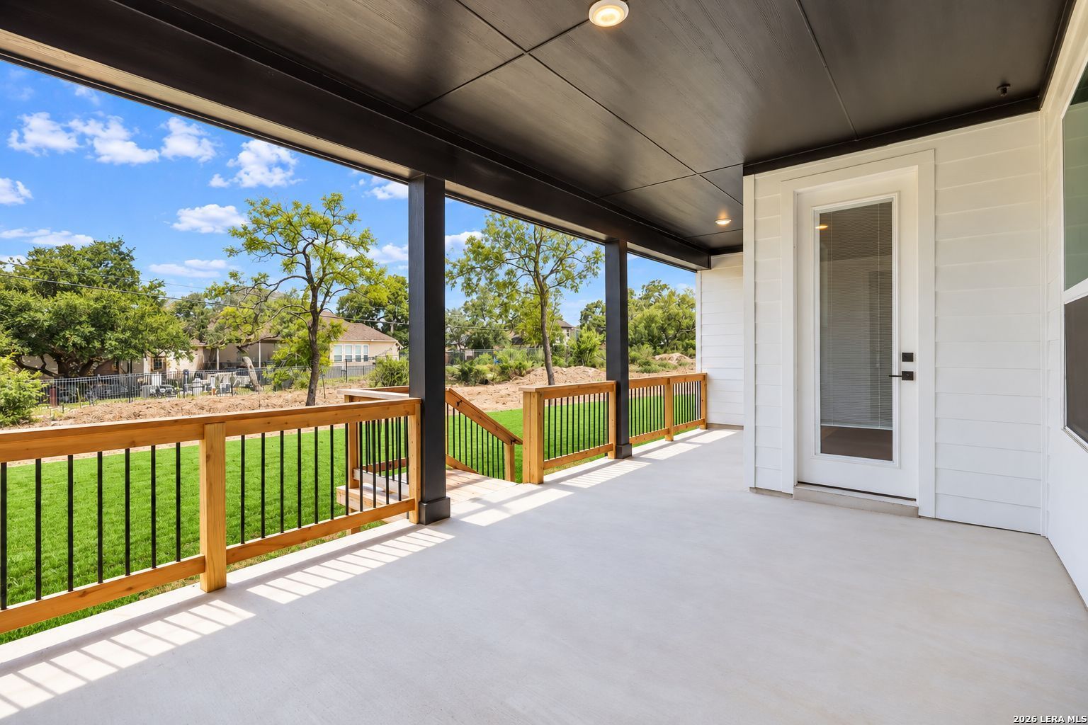 Covered patio with wood railings overlooking fenced backyard at Davidson Homes The Oxford F in Potranco Oaks, Castroville, Texas