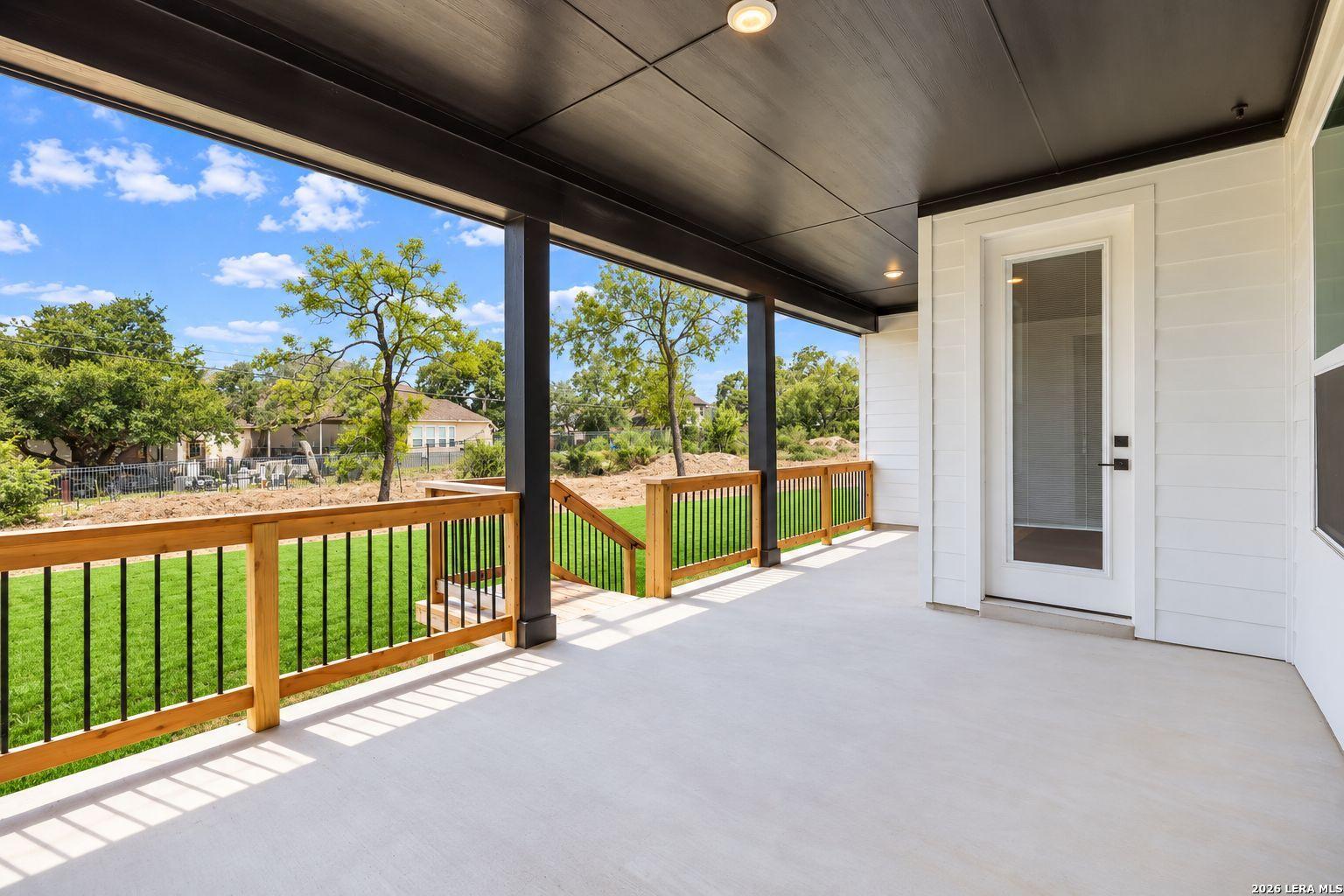 Covered patio with wood railings overlooking fenced backyard at Davidson Homes The Oxford F in Potranco Oaks, Castroville, Texas