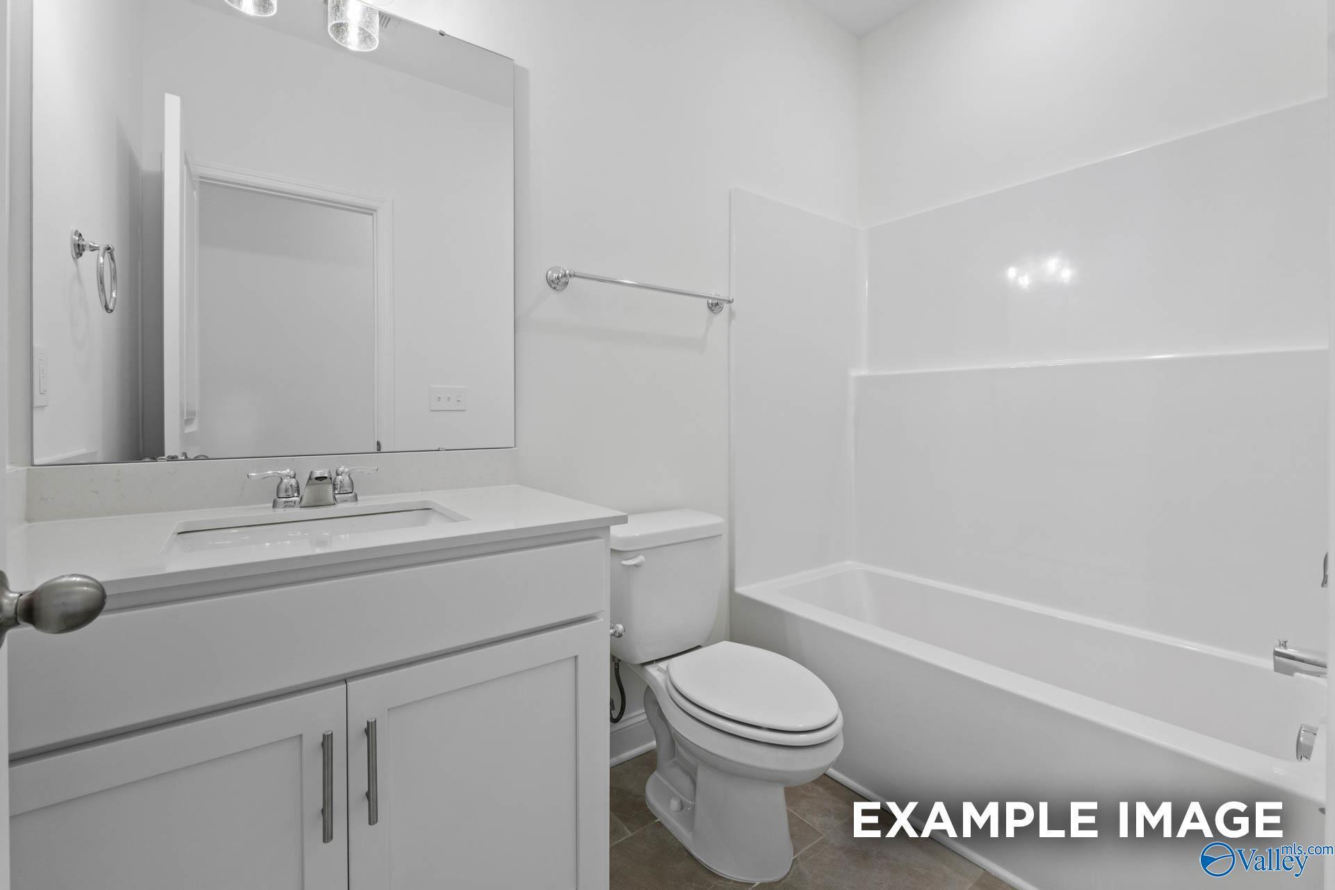 Bright white full bathroom with bathtub, vanity sink, mirror, and toilet in Davidson Homes The Rockford B, The Meadows, Athens, Alabama