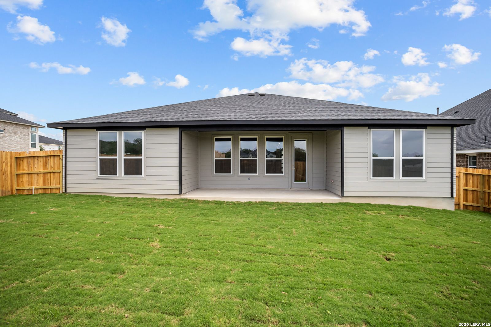 Covered back patio and spacious lawn of a 1-story Lanier G floor plan home in The Reserve at Potranco Oaks, Castroville.
