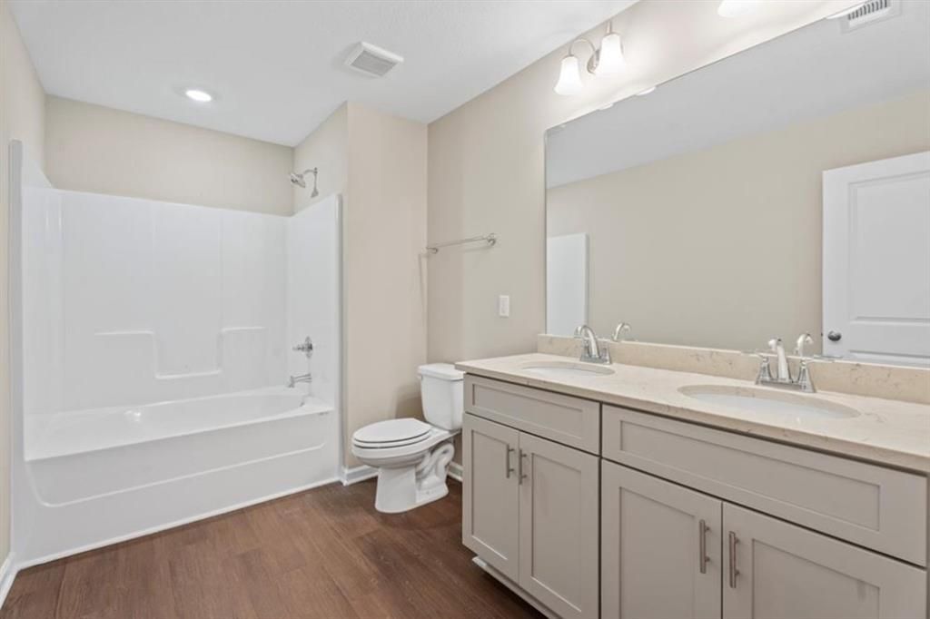 Modern master bathroom with double vanity, tub-shower combo, and wood floors in Davidson Homes The Washington, Phenix City, Alabama