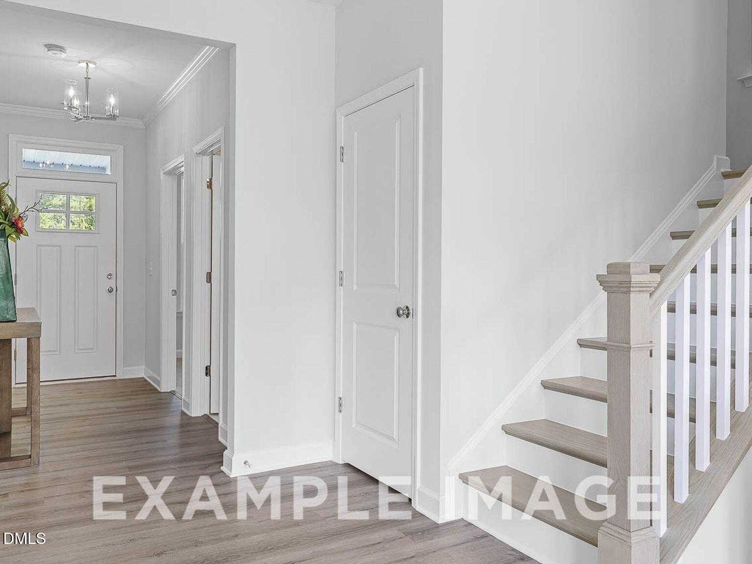 Bright two-story foyer with oak staircase, hardwood floors, chandelier, and console table in Davidson Homes Chestnut B, Lillington, NC