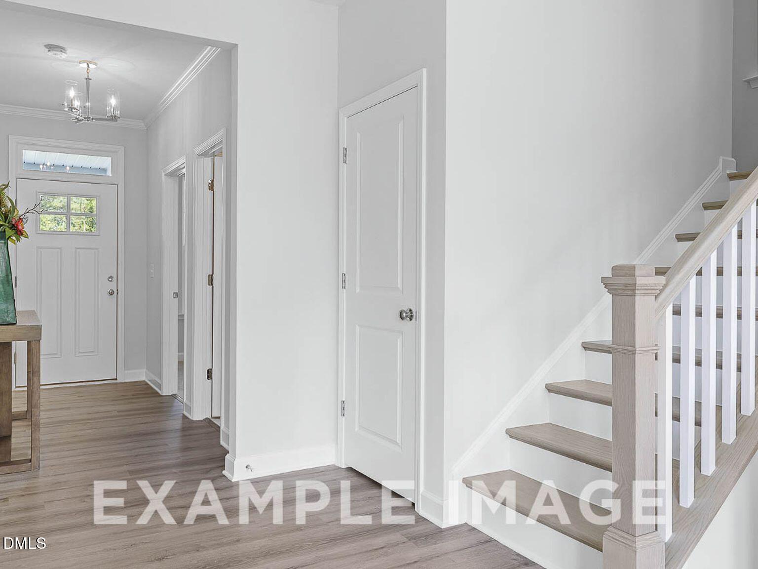 Bright two-story foyer with oak staircase, hardwood floors, chandelier, and console table in Davidson Homes Chestnut B, Lillington, NC