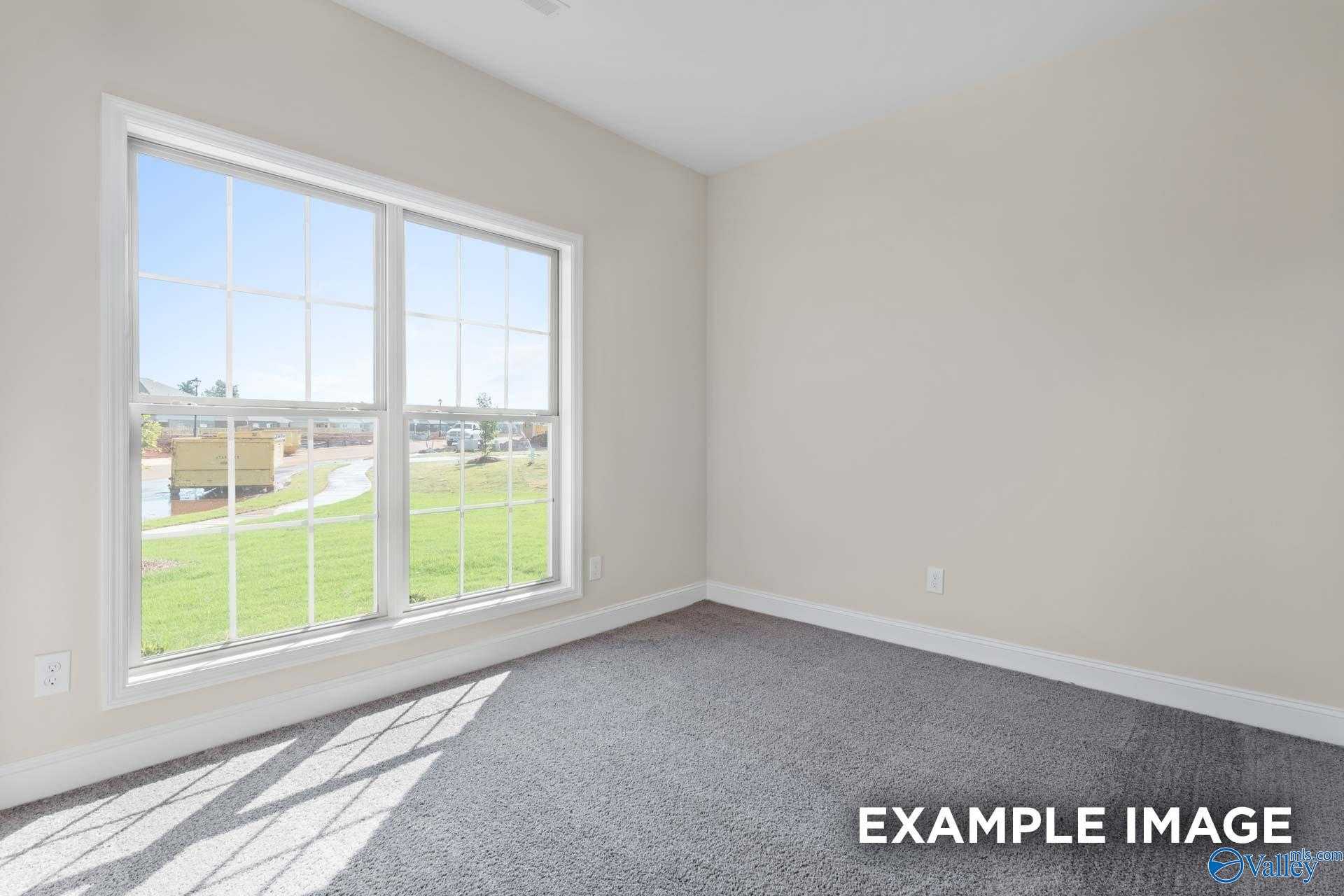 Sunlit secondary bedroom with large windows overlooking green lawn and gray carpet in The Asheville home, Arab, Alabama