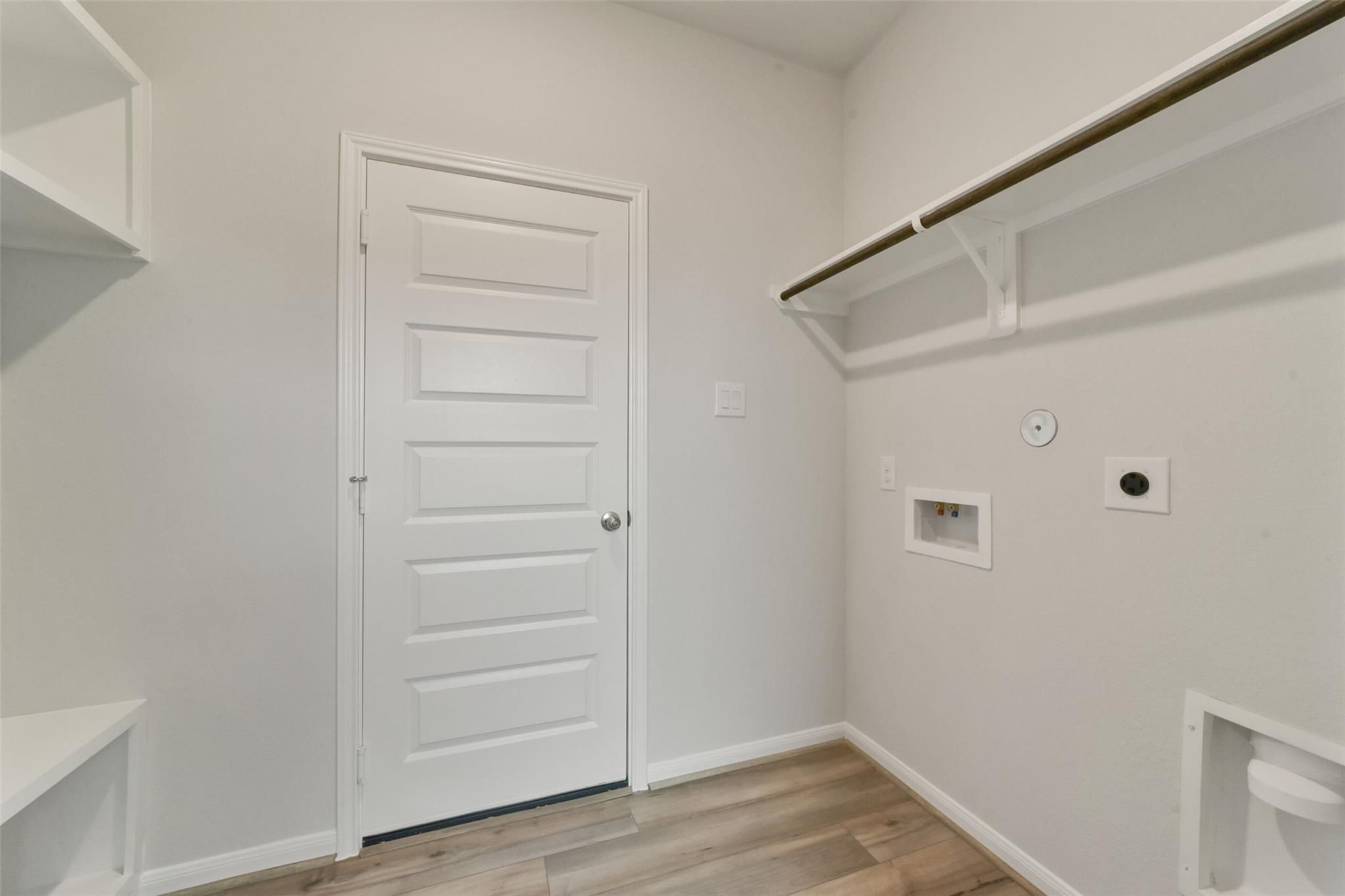 Functional laundry room featuring utility sink, open shelving, and washer/dryer hookups in Davidson Homes San Marcos E, Beasley, Texas