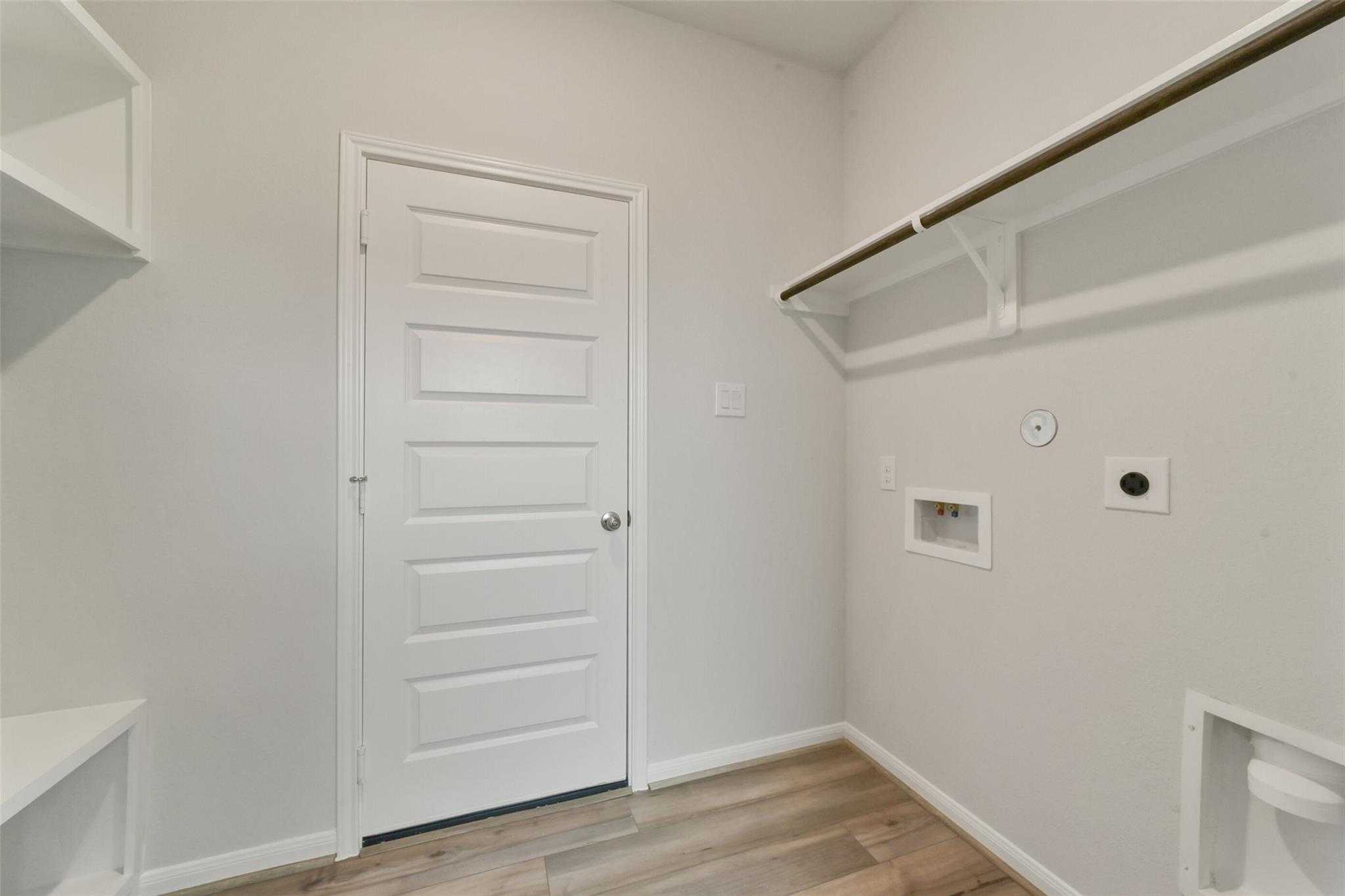 Functional laundry room featuring utility sink, open shelving, and washer/dryer hookups in Davidson Homes San Marcos E, Beasley, Texas