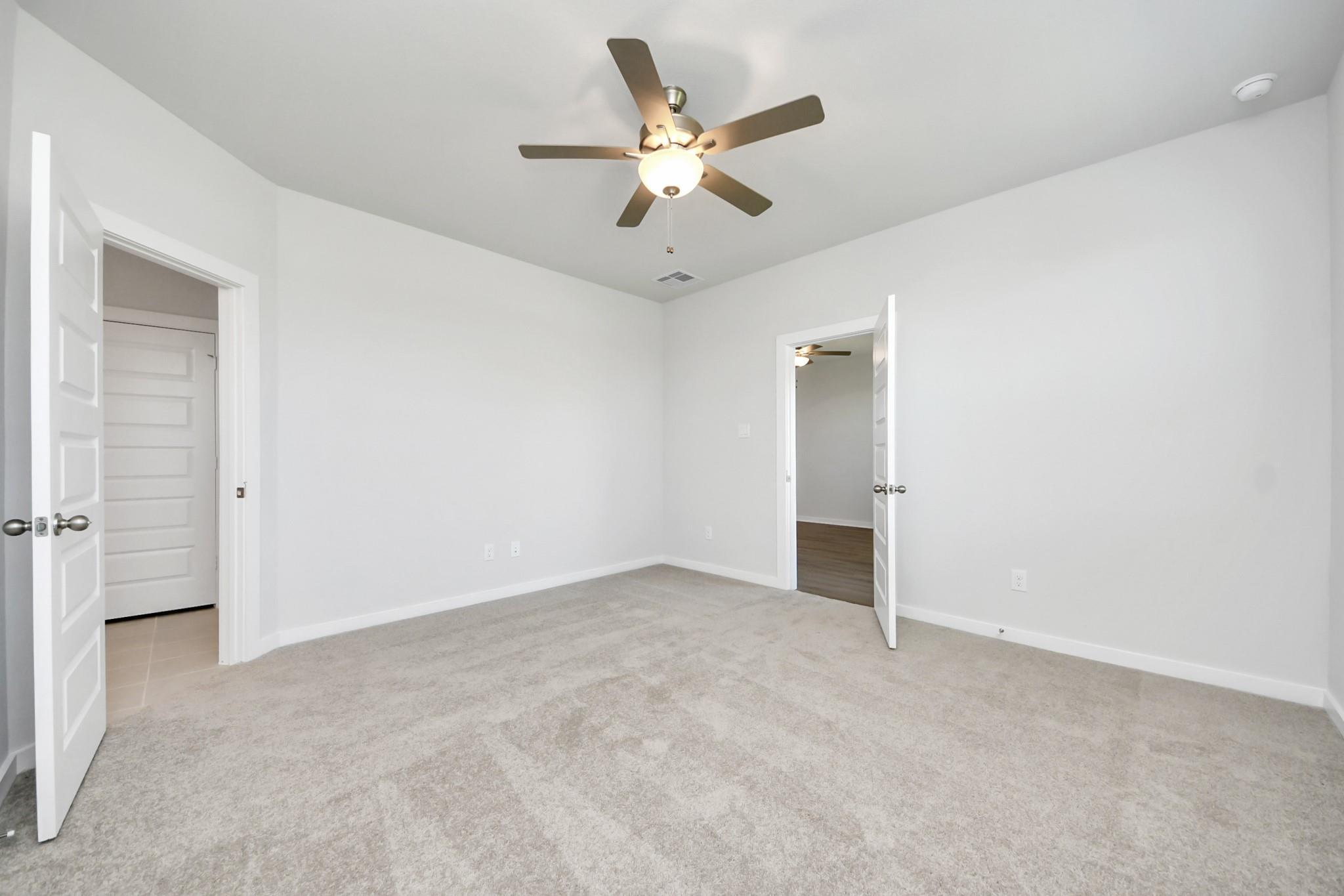Bright bedroom with carpet flooring and ceiling fan in Davidson Homes' The Costa A plan, Emberly, Beasley, TX