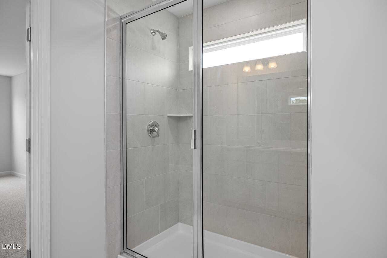 Modern frameless glass shower with subway tile walls and niche shelf in master bath of 5-bedroom Hickory II B home, Zebulon, NC