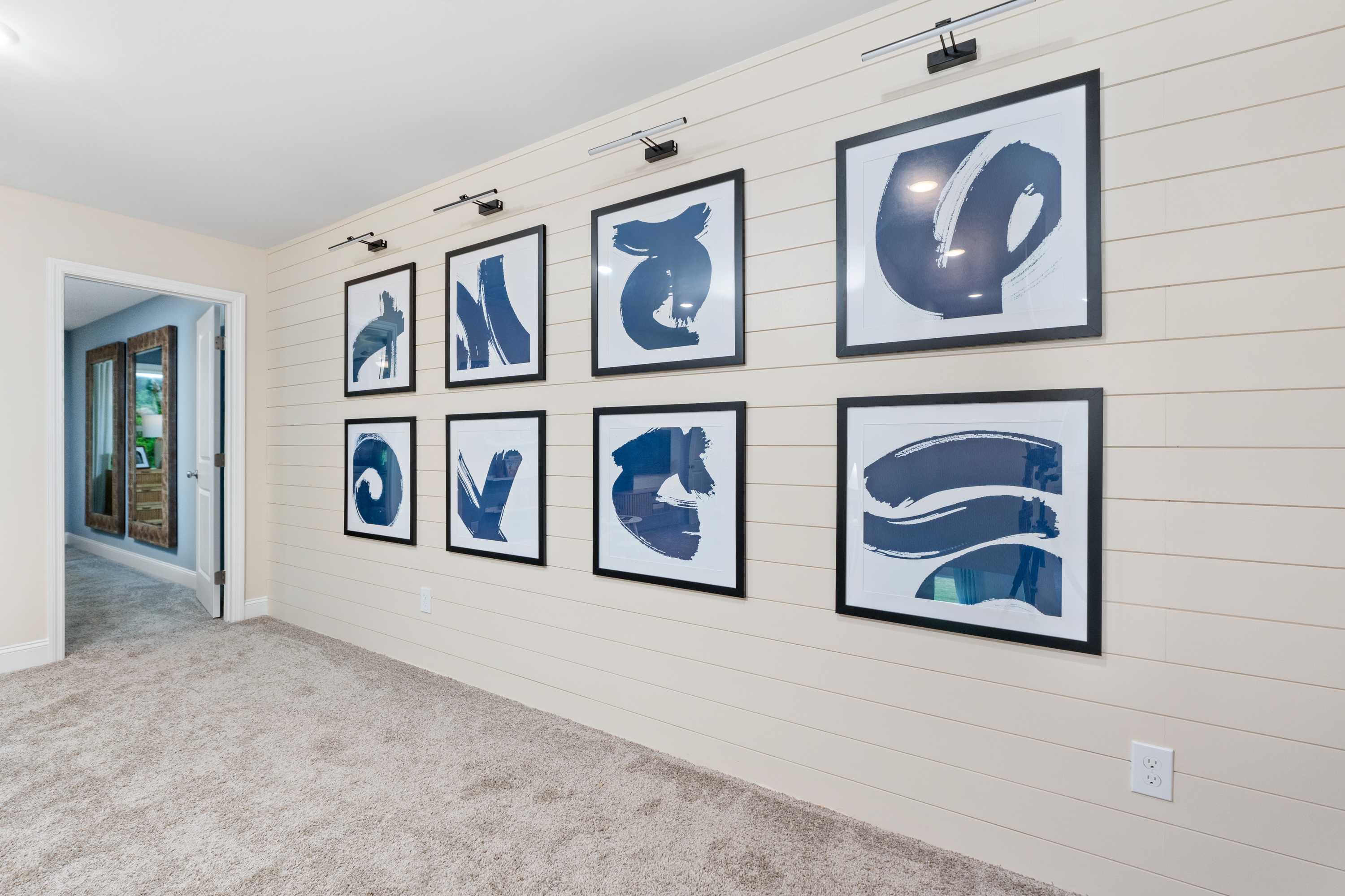 Gallery wall of navy abstract artworks in shiplap hallway at Pavilion Huntsville AL by Davidson Homes