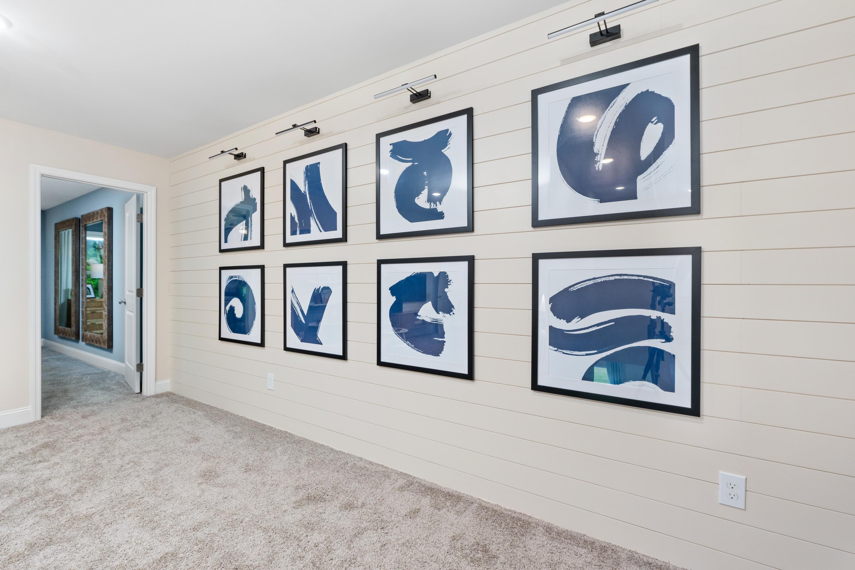 Gallery wall of navy abstract artworks in shiplap hallway at Pavilion Huntsville AL by Davidson Homes