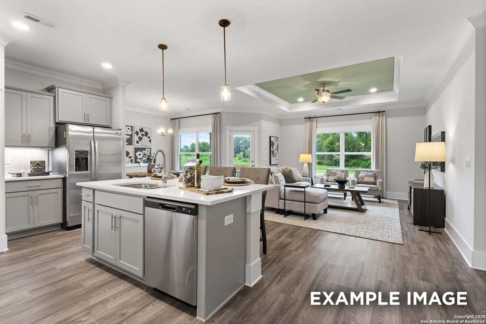 Open-concept kitchen-living area with white cabinets, stainless appliances, large island, and large windows in The Daphne H, Seguin, Texas
